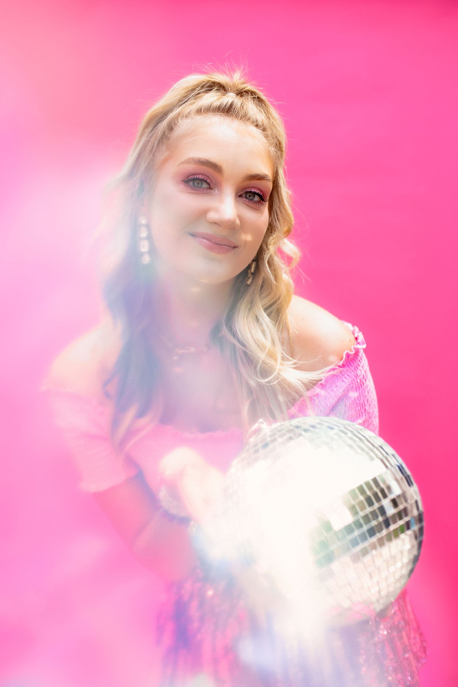 Dreamy pink photoshoot with disco ball creating sparkly light effects.