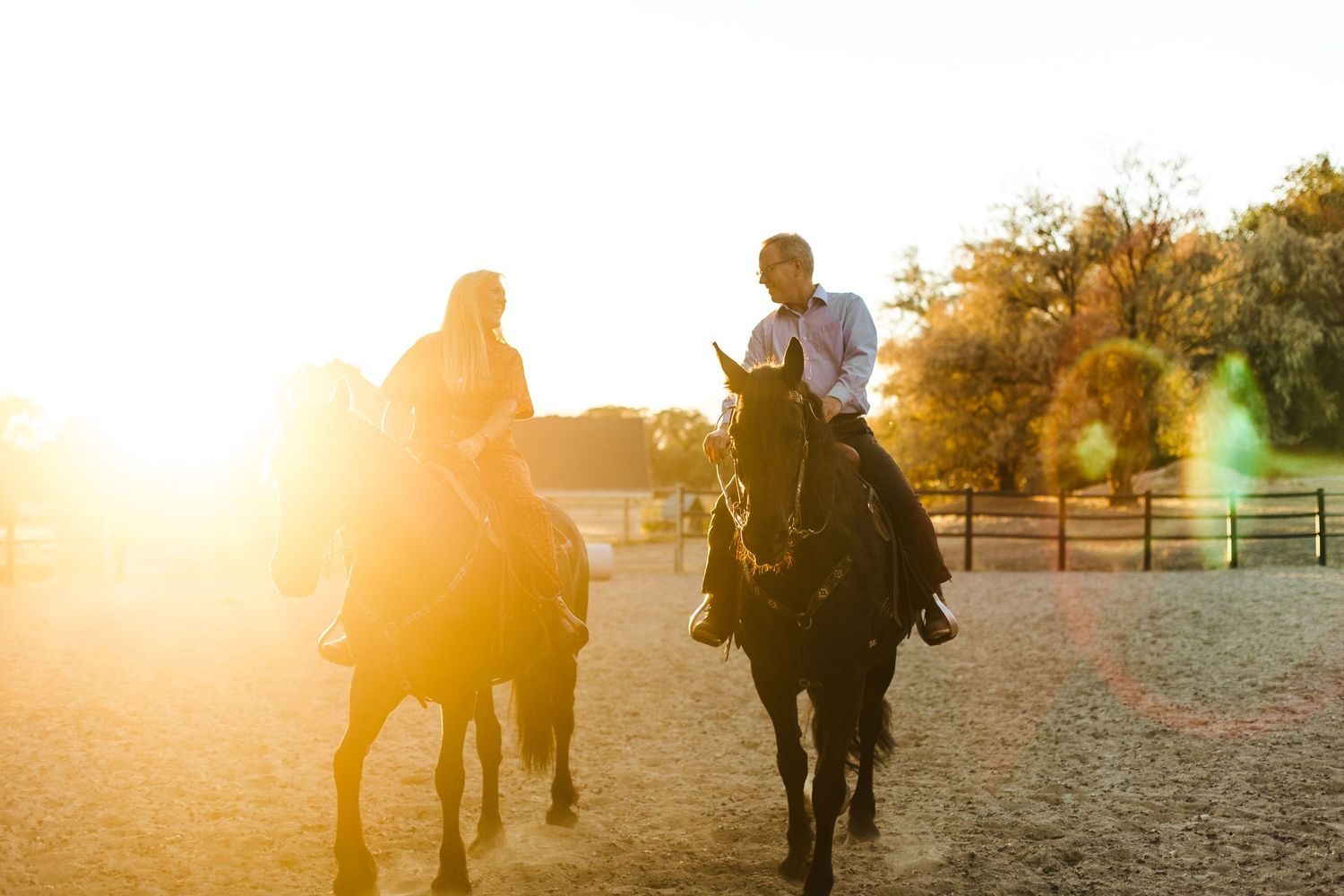 Silhouettes of people walking with horses against a golden sunset backdrop.
