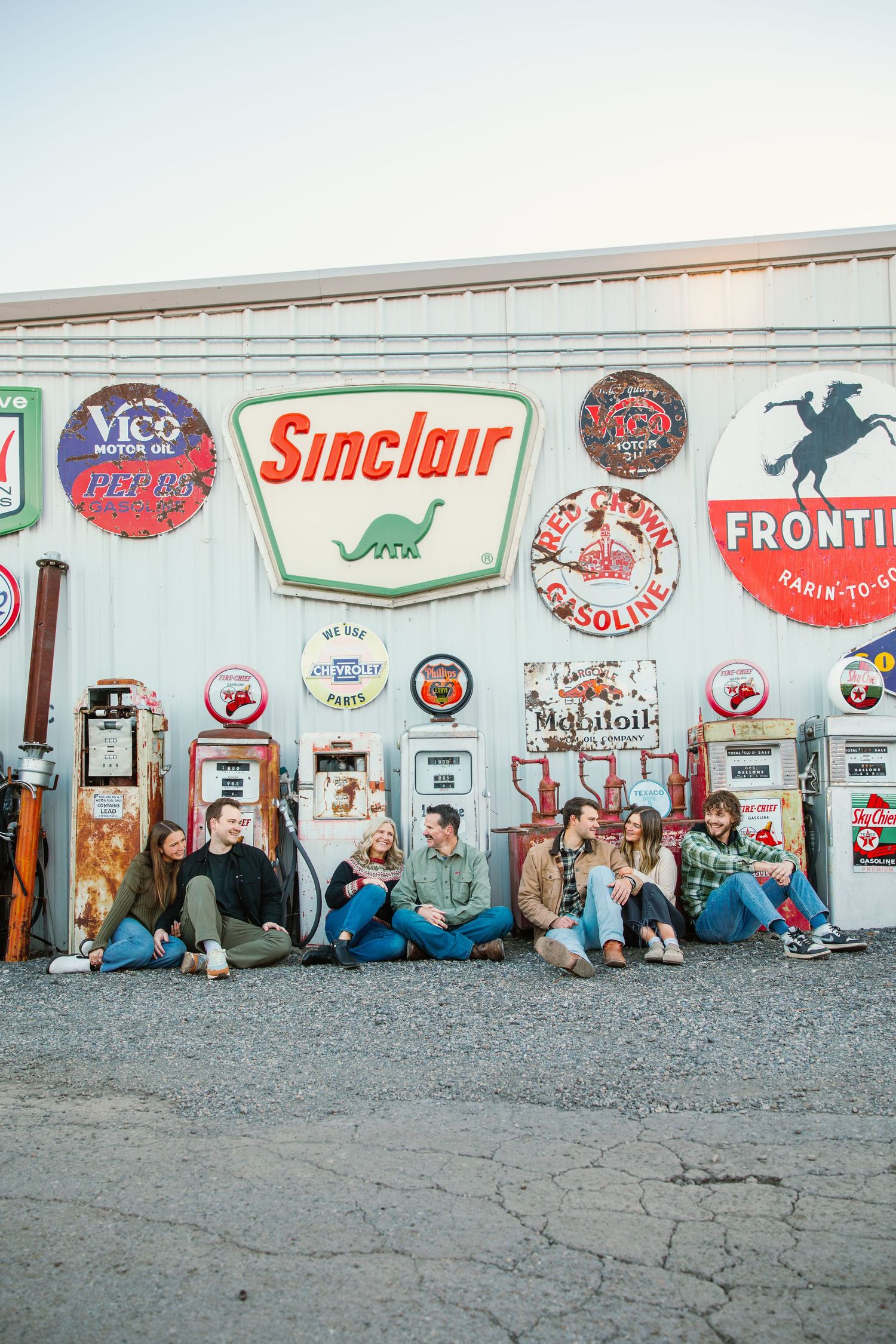 Group sitting against wall decorated with vintage Sinclair and gas station signs.