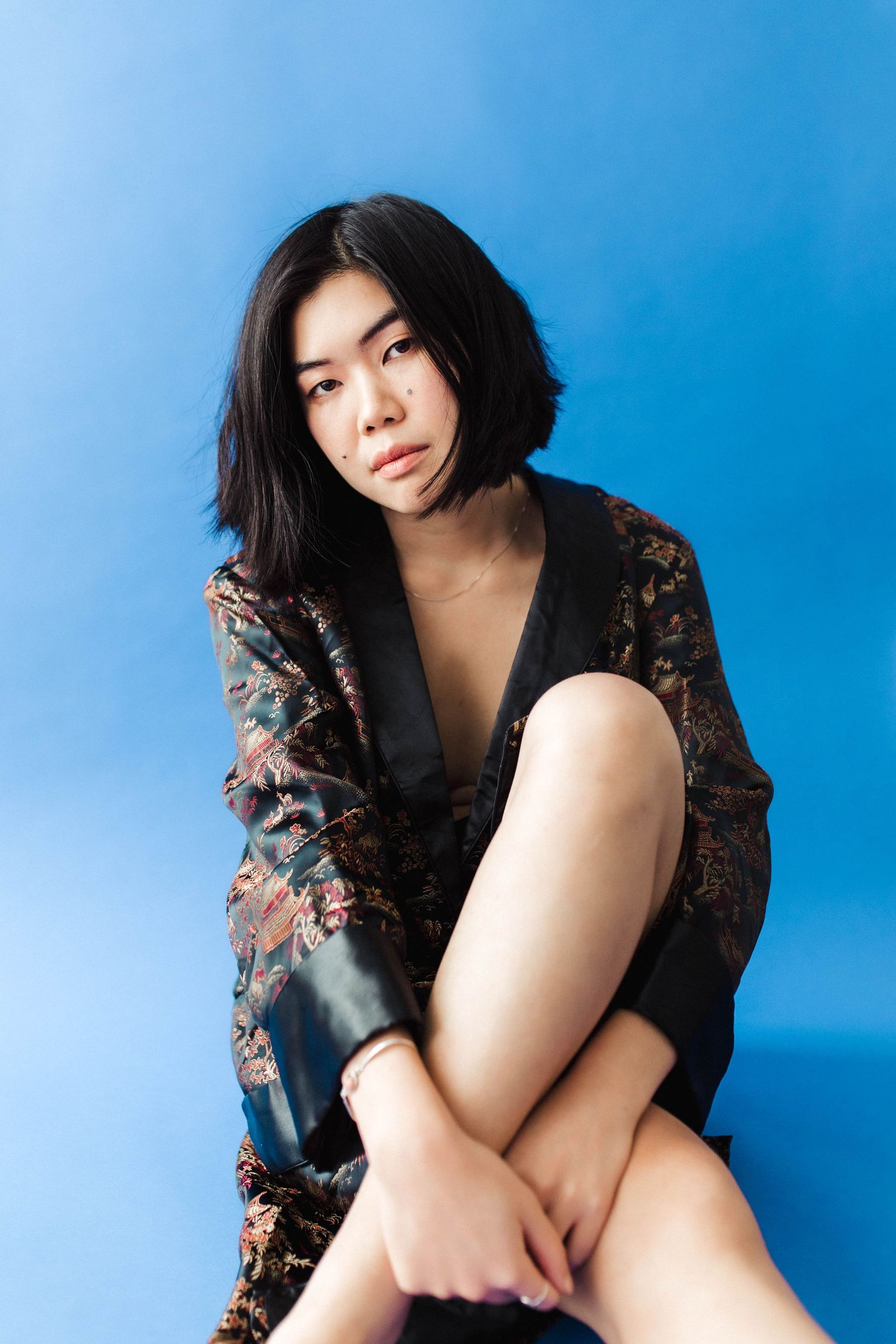 Portrait series against bright blue background wearing patterned dark top.