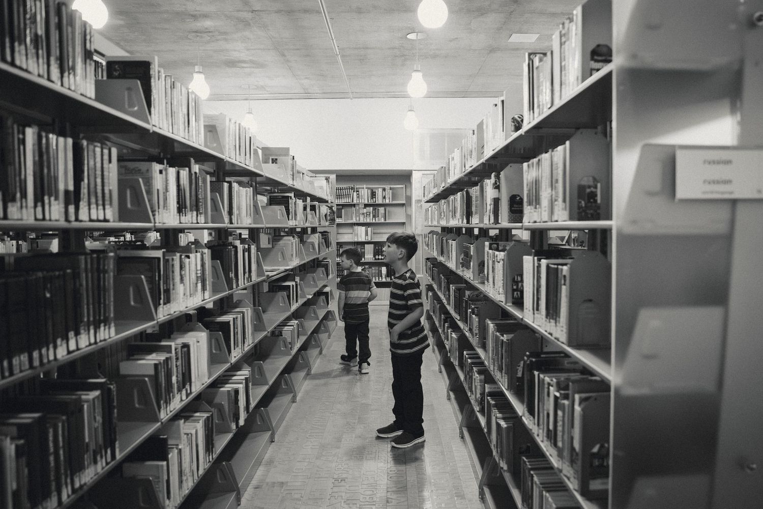 Black and white interior view of library shelves extending down long corridors.