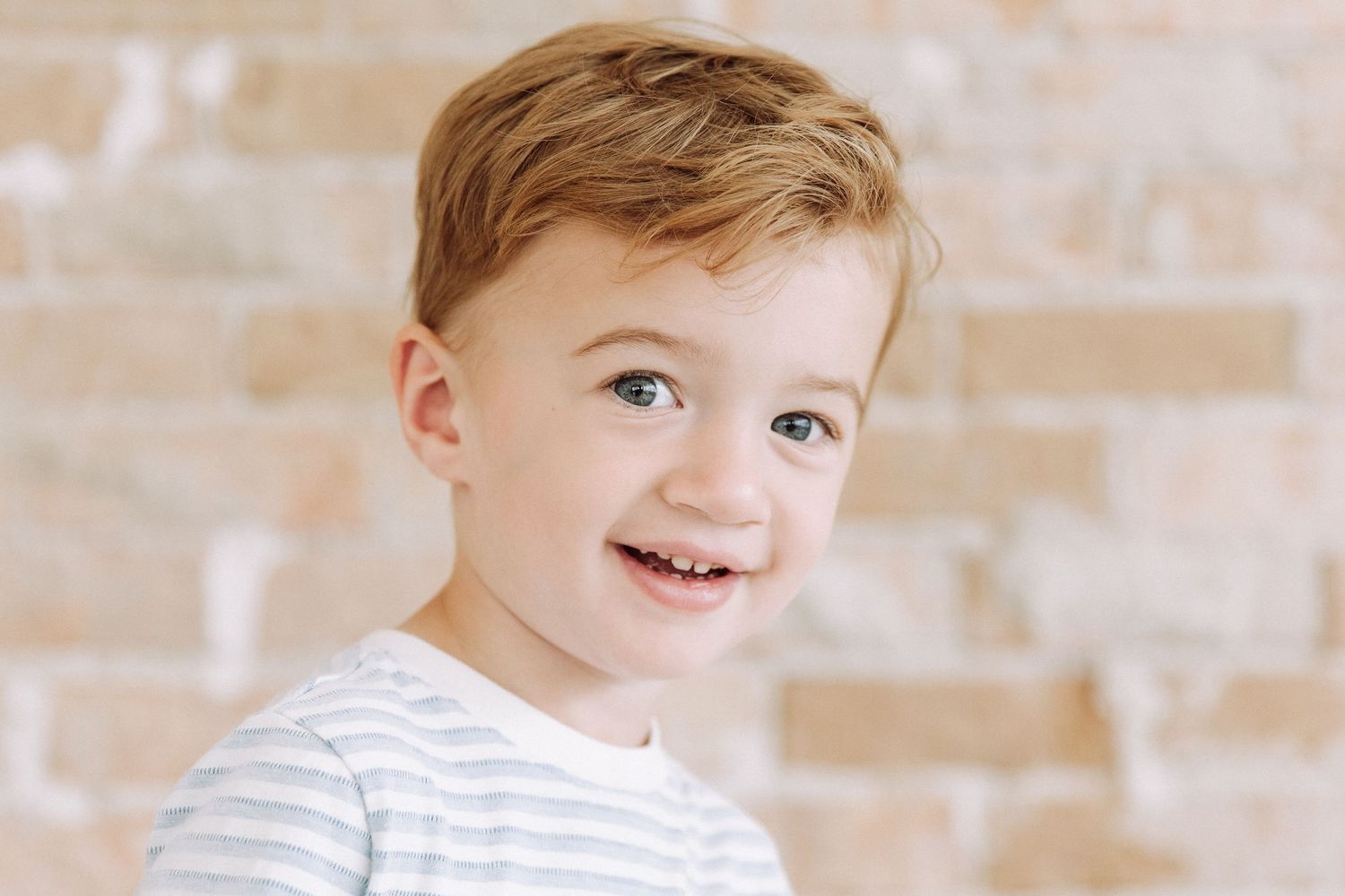 Studio portrait series against brick wall background in natural light.