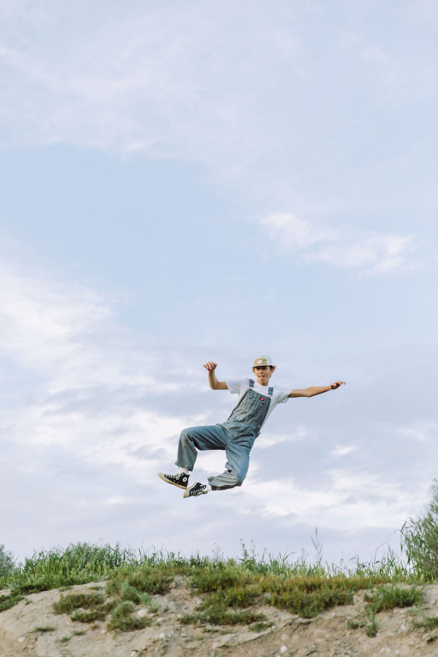 Dynamic sequence of a person jumping and leaping across a hilltop against a blue sky.