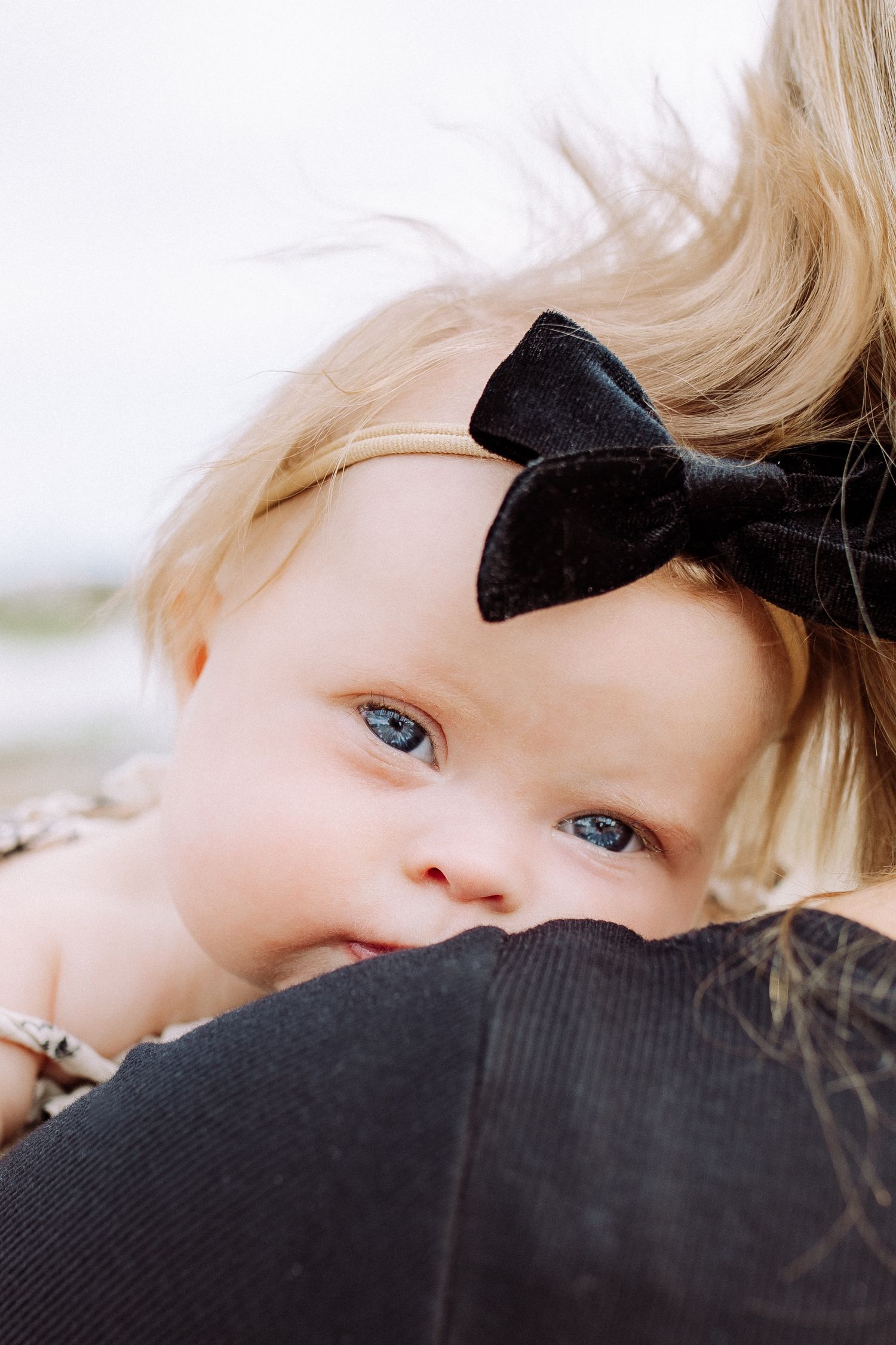 Close-up portrait showing blue eyes and blonde hair against dark fabric.