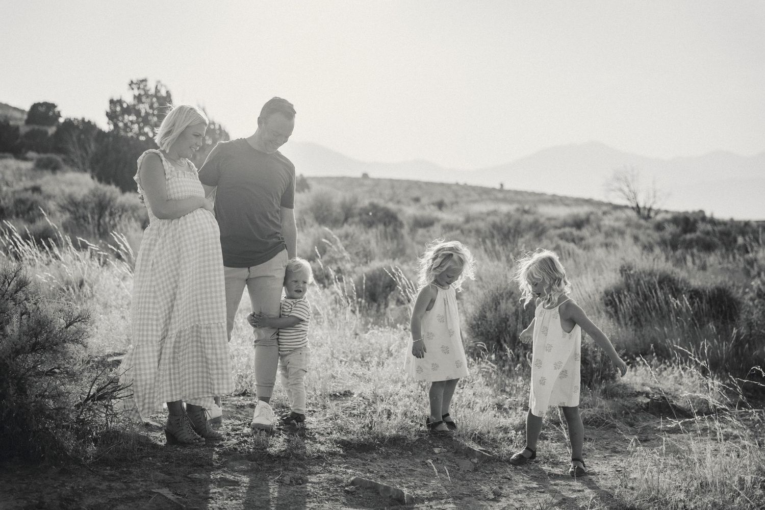 Silhouetted family figures walking together through a desert landscape at sunset.
