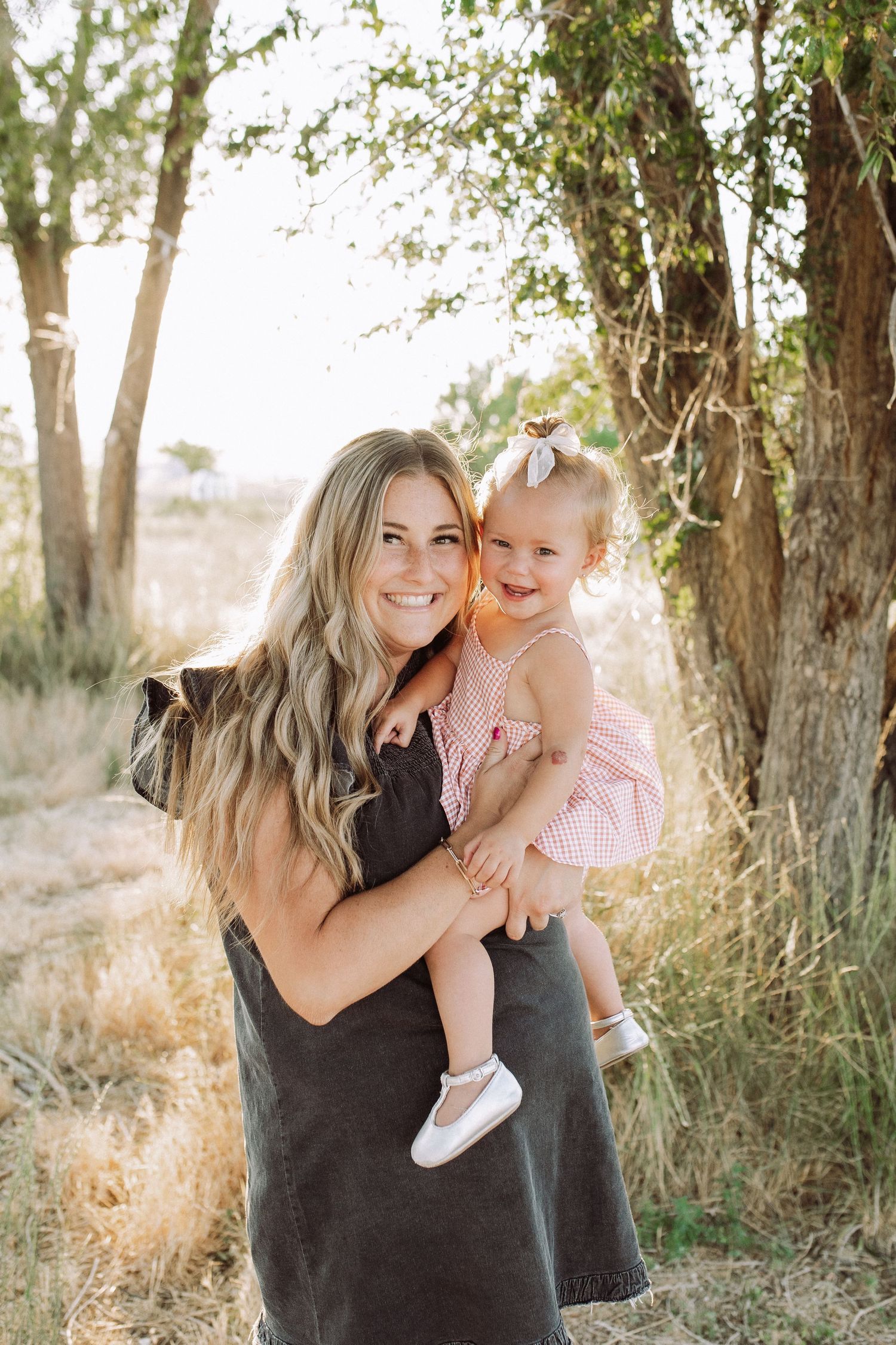 Mother and child share joyful moments together in a wooded outdoor setting.