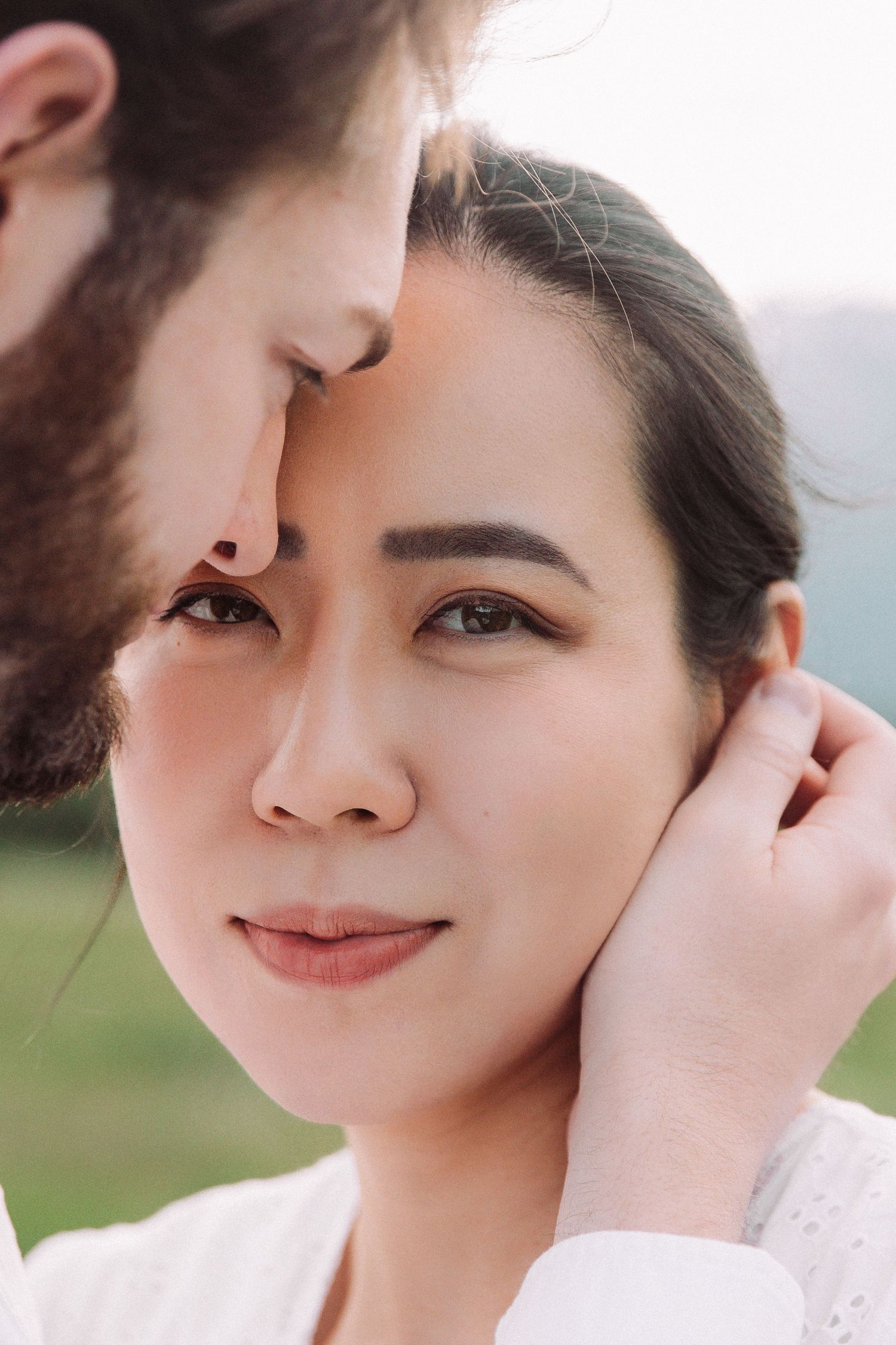 A tender romantic moment captured in close-up against a soft natural background.