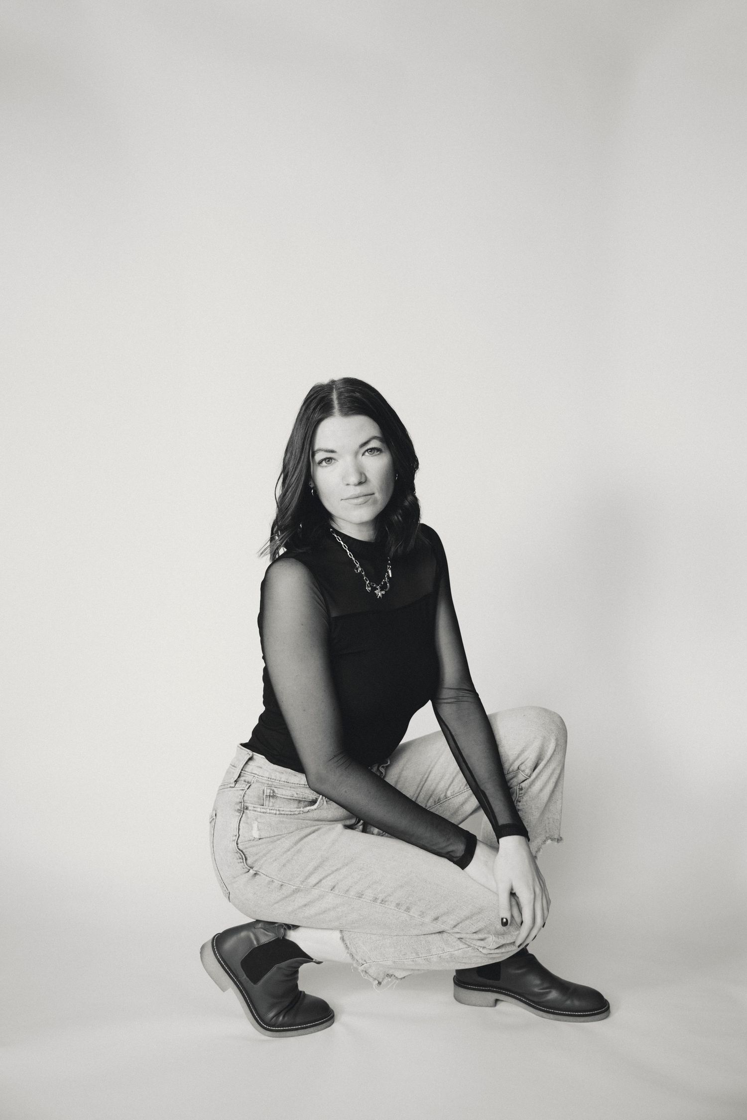 Black and white portrait series showing person in dark top sitting on light background.