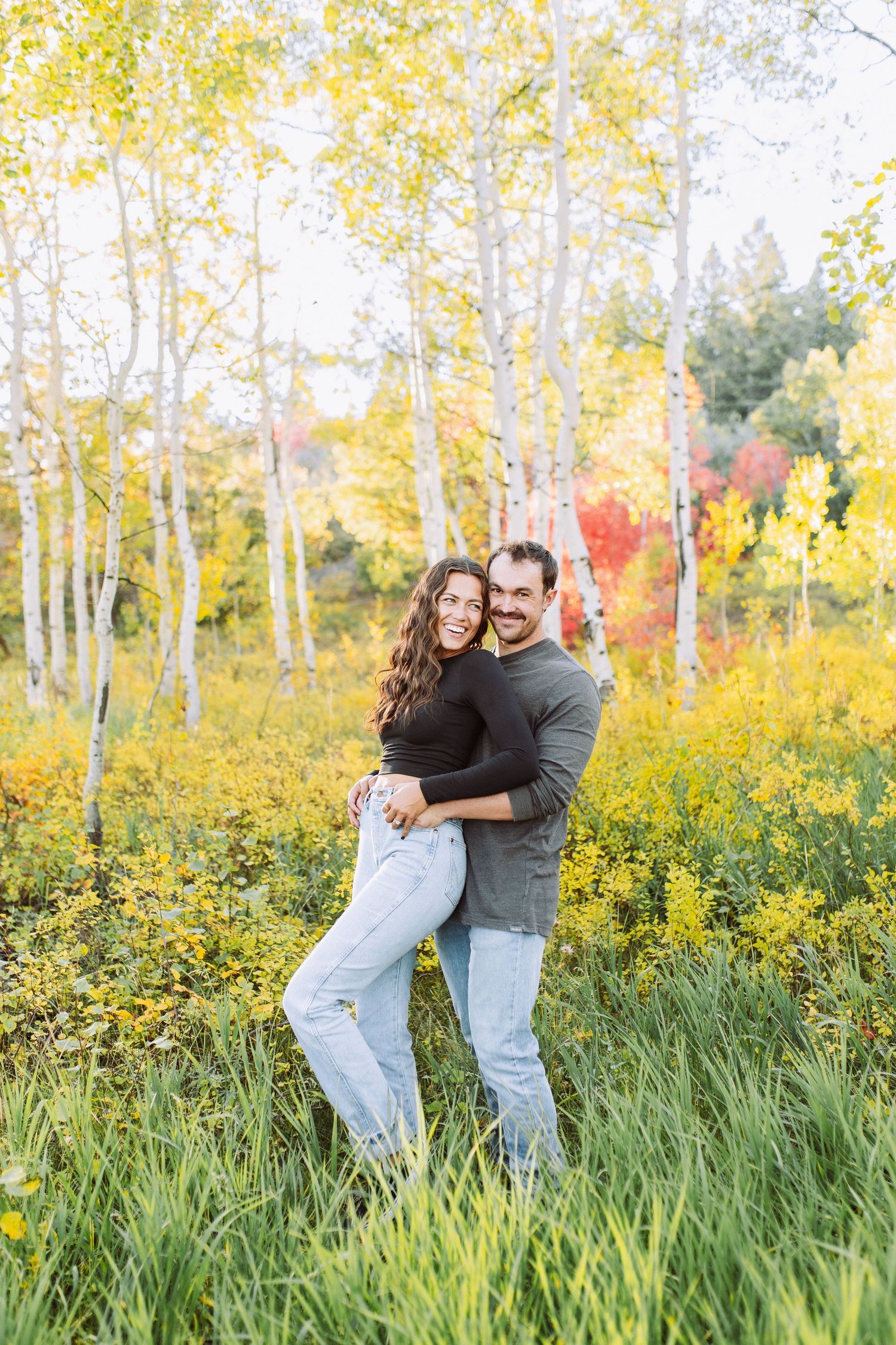 A couple embraces in a golden aspen grove during autumn.