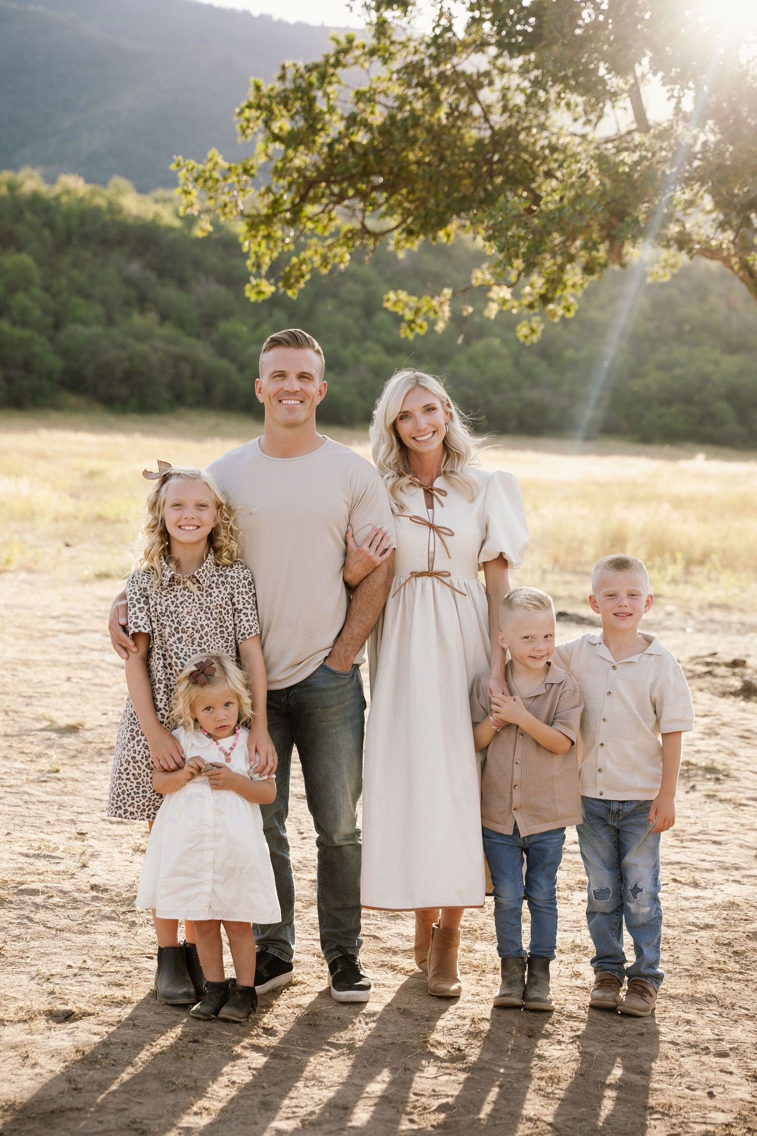 Family portrait session at golden hour in a field with beautiful backlit sunlight creating silhouettes.