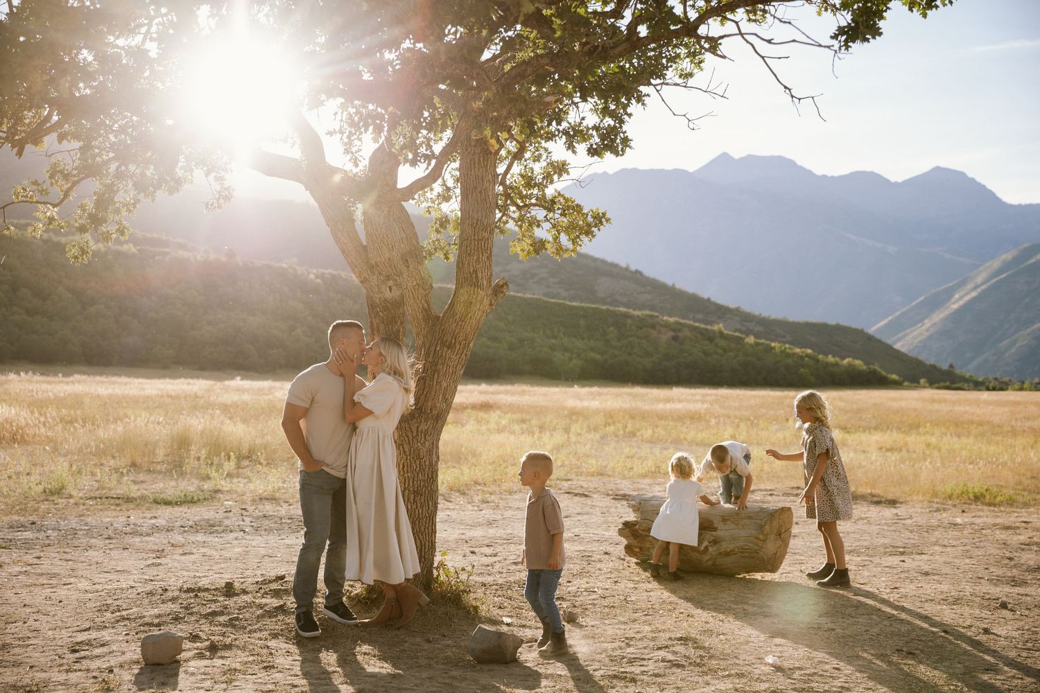 Silhouettes of people walking through a golden field at sunset with mountains in the background.