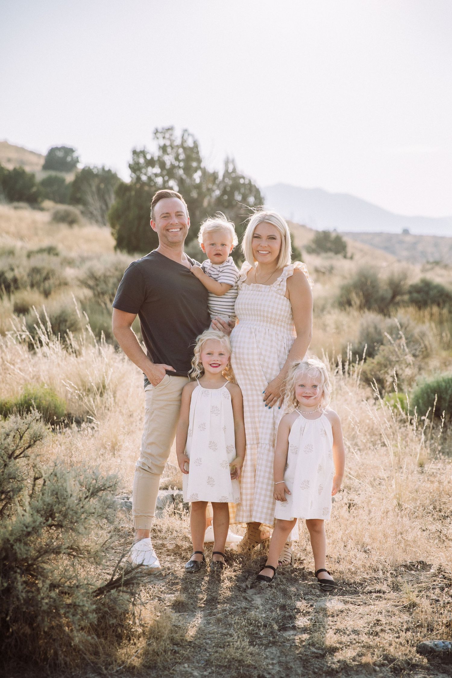 Family portrait in a desert landscape with sage brush and mountains in the background.