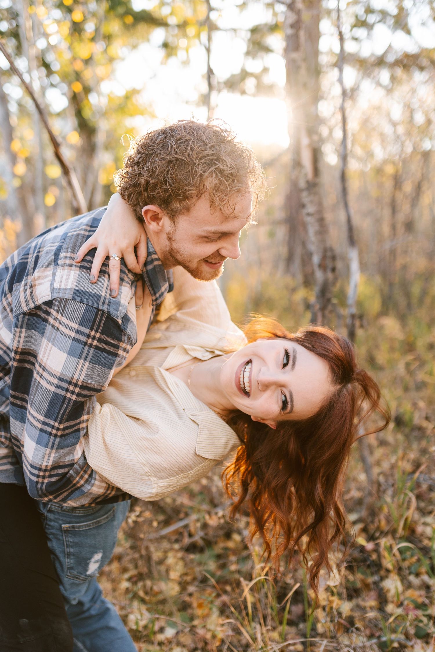 Playful dip pose between couple surrounded by autumn aspens at golden hour.
