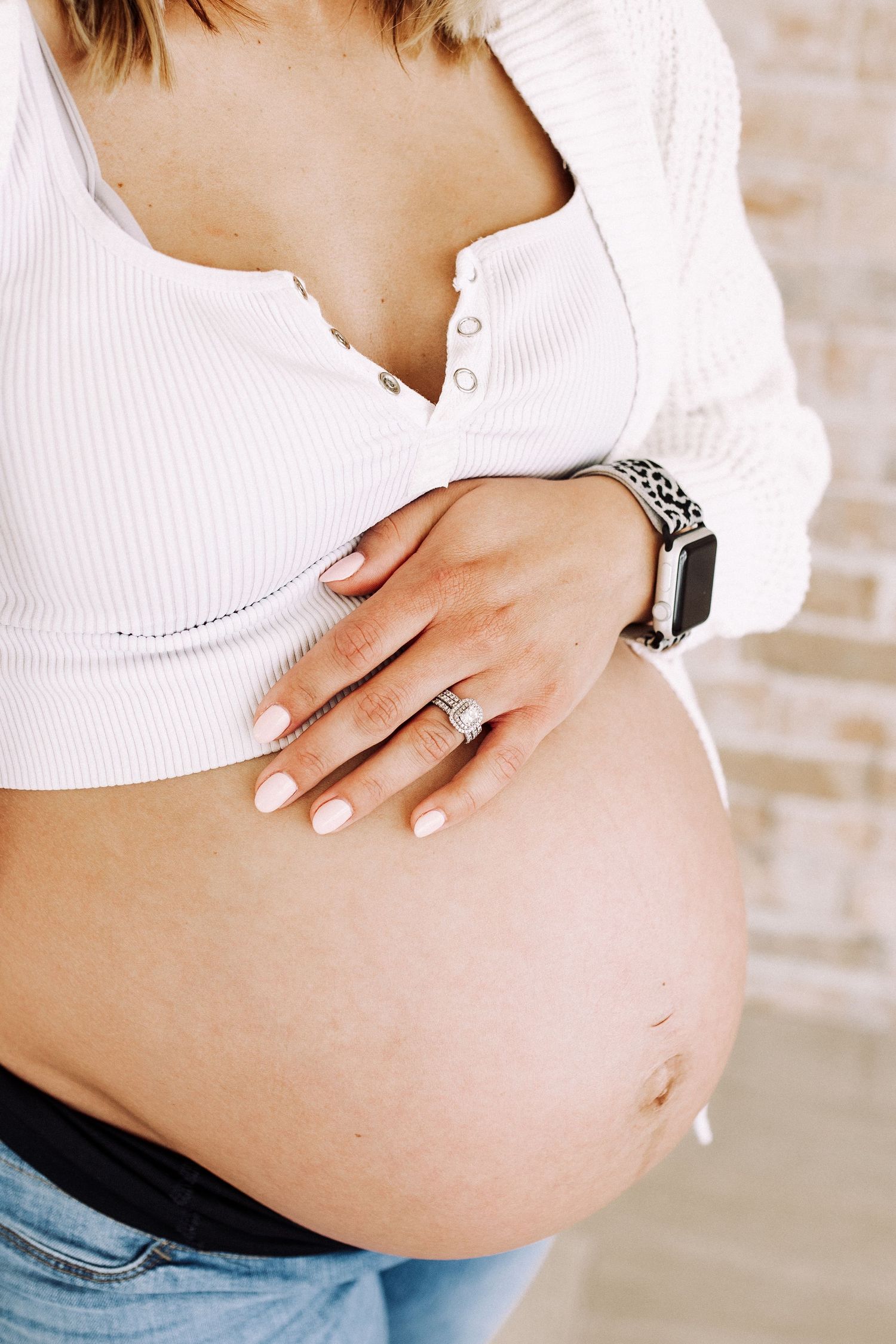 A series of pregnancy progression photos showing a growing baby bump in a white top.