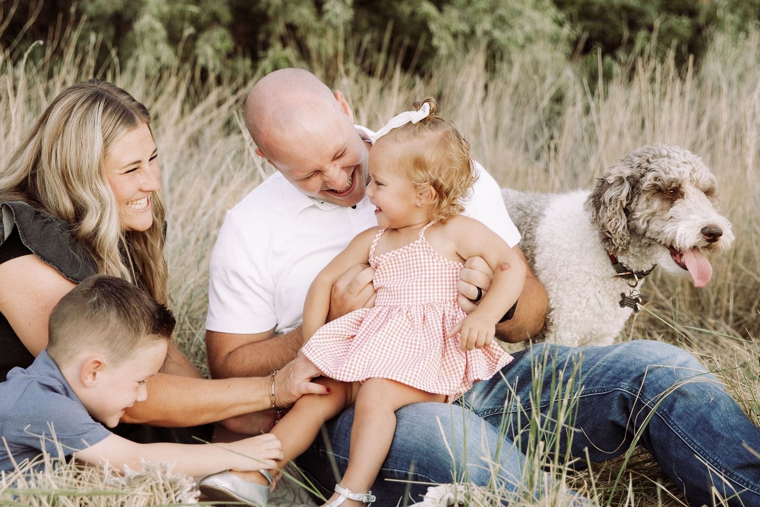 Family and their white dog enjoy quality time together outdoors in natural setting.