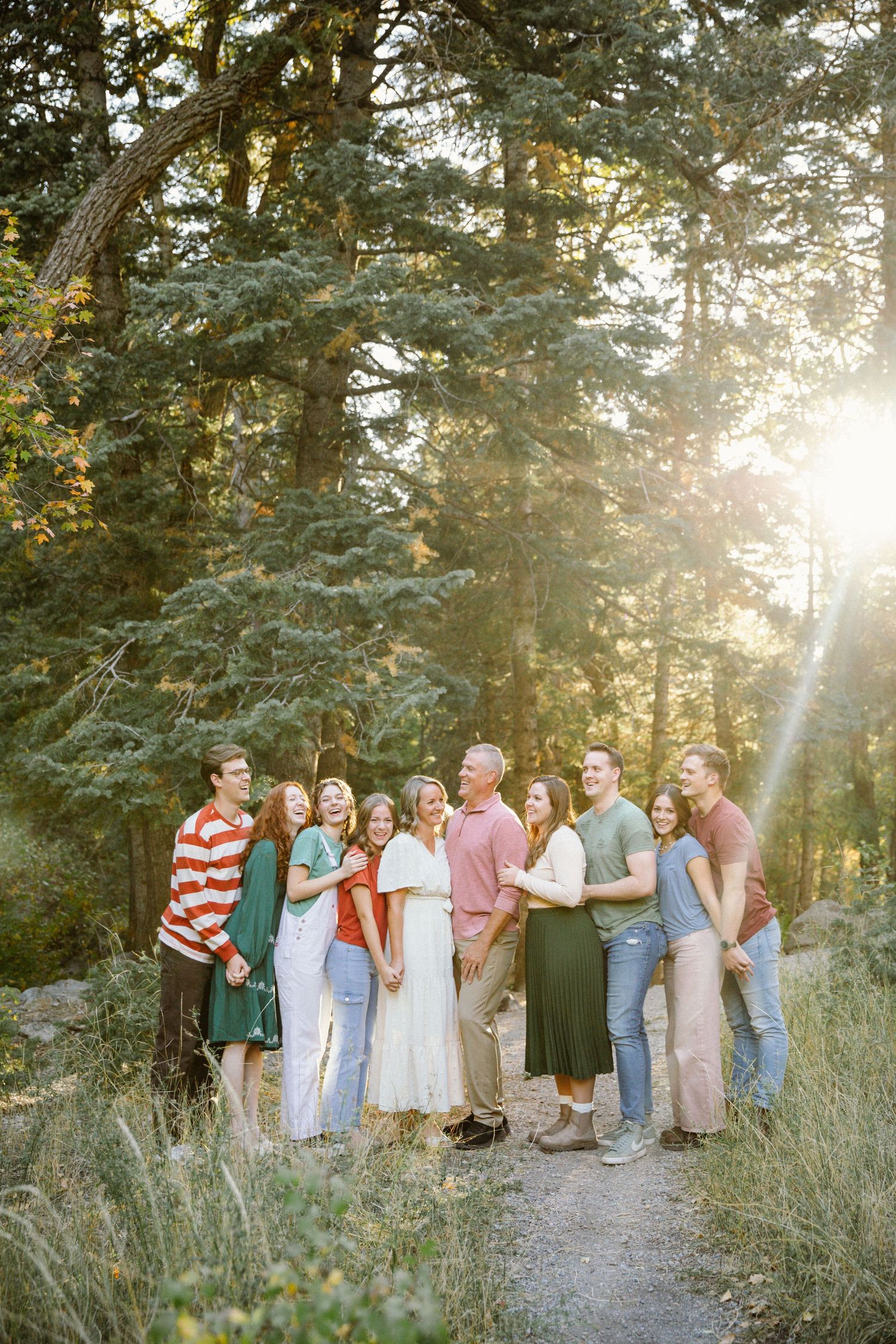 Large family gathering photographed on a nature trail with sunlight filtering through trees.