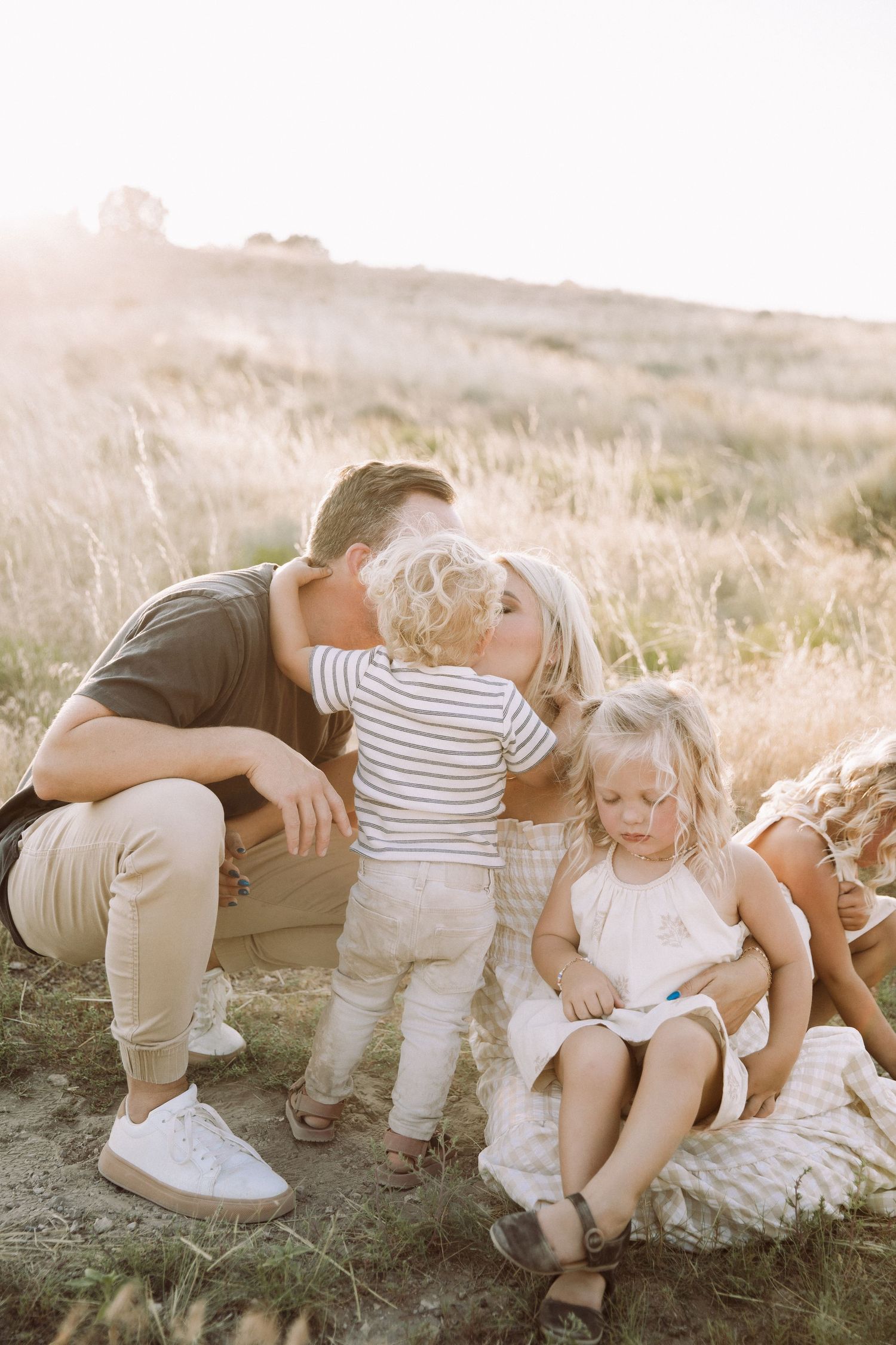 Family lounging together on ground during golden hour photoshoot in desert setting.