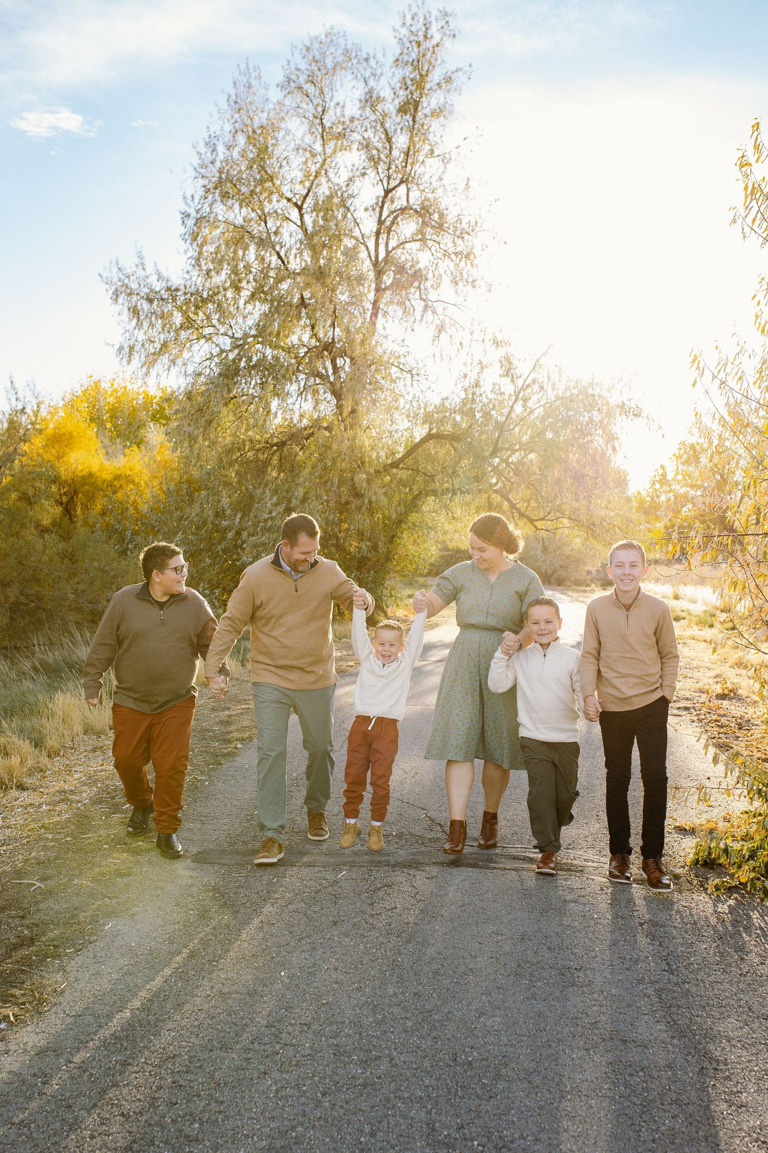 Group walking together on dirt path at sunset with trees in background.
