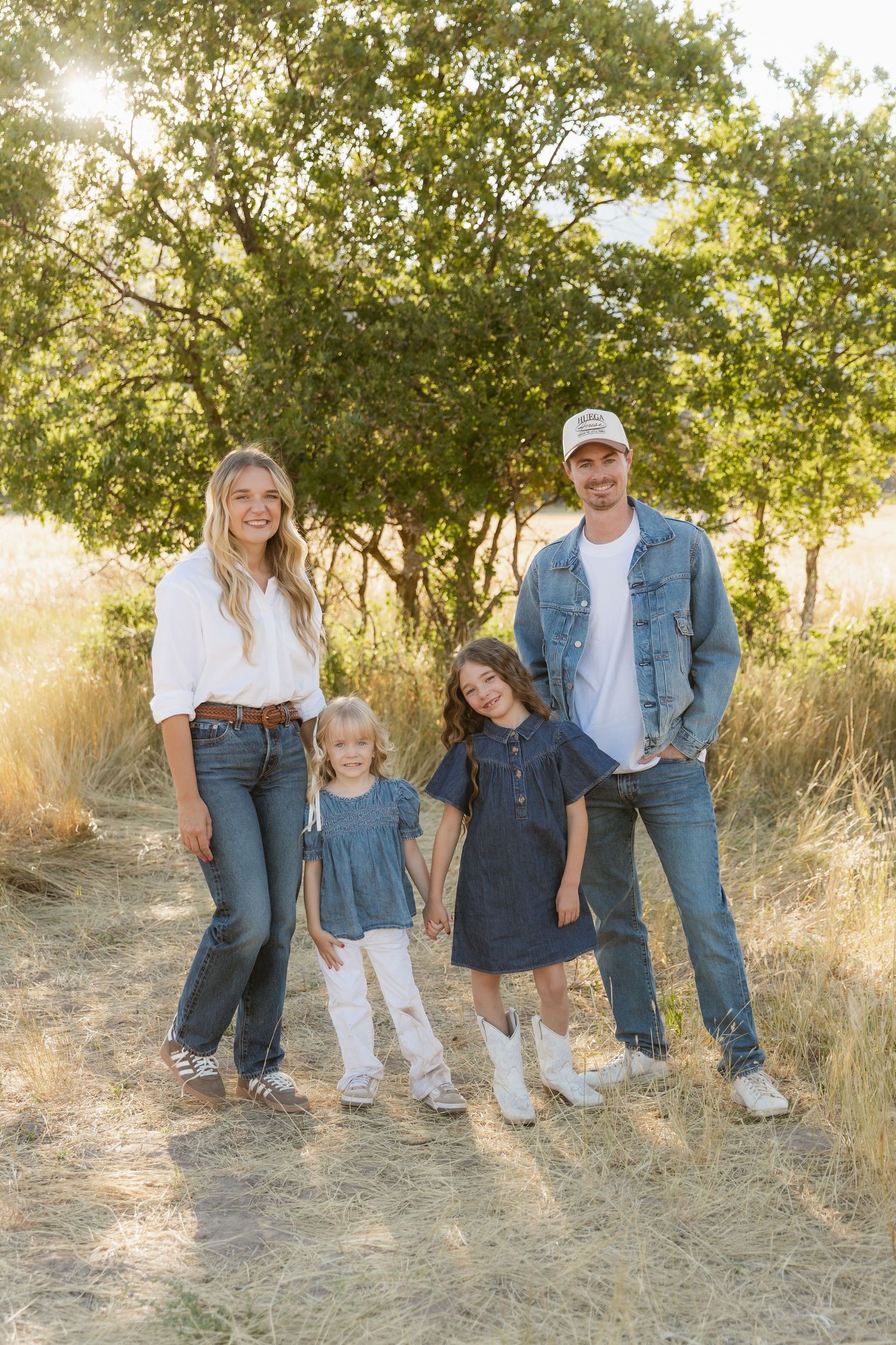 A group poses together on a dirt path during golden hour with trees and sunlight in the background.
