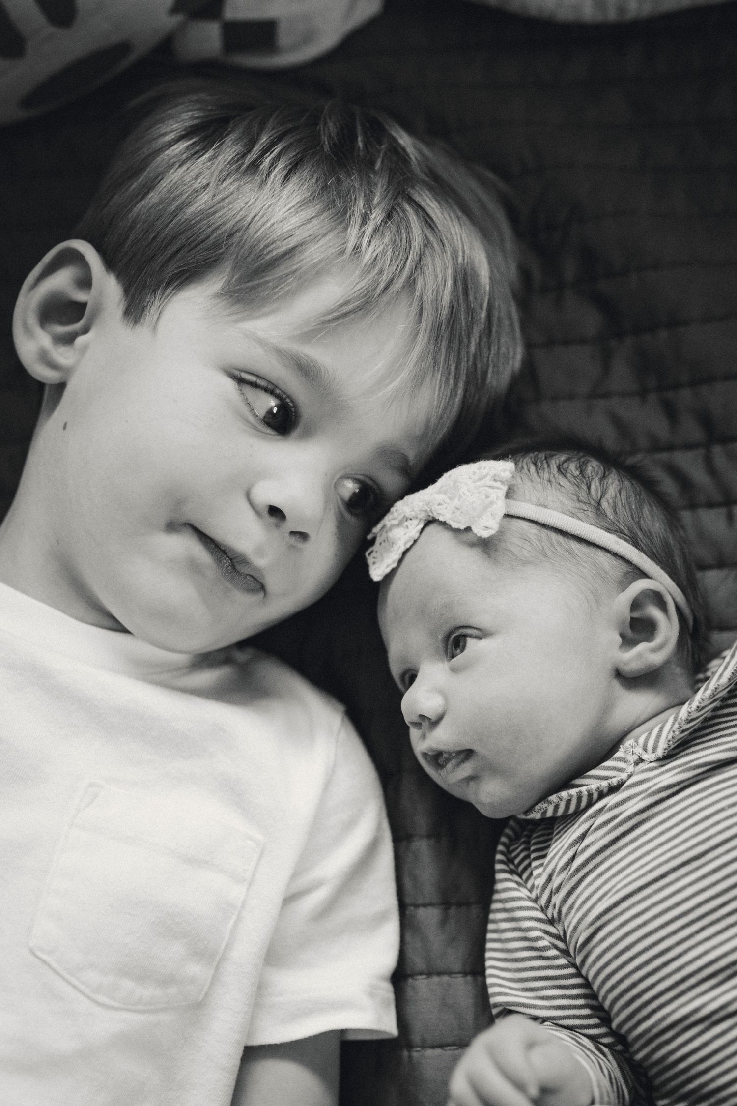Sweet black and white portrait of siblings lying together on a blanket.