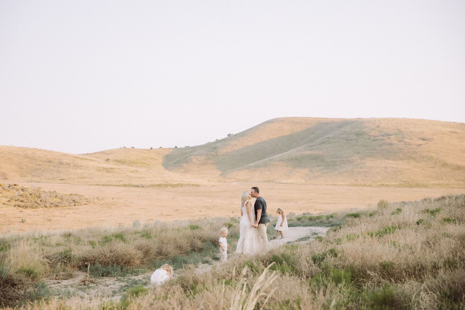 Wide landscape shot of desert hills with figures in distance during sunset.