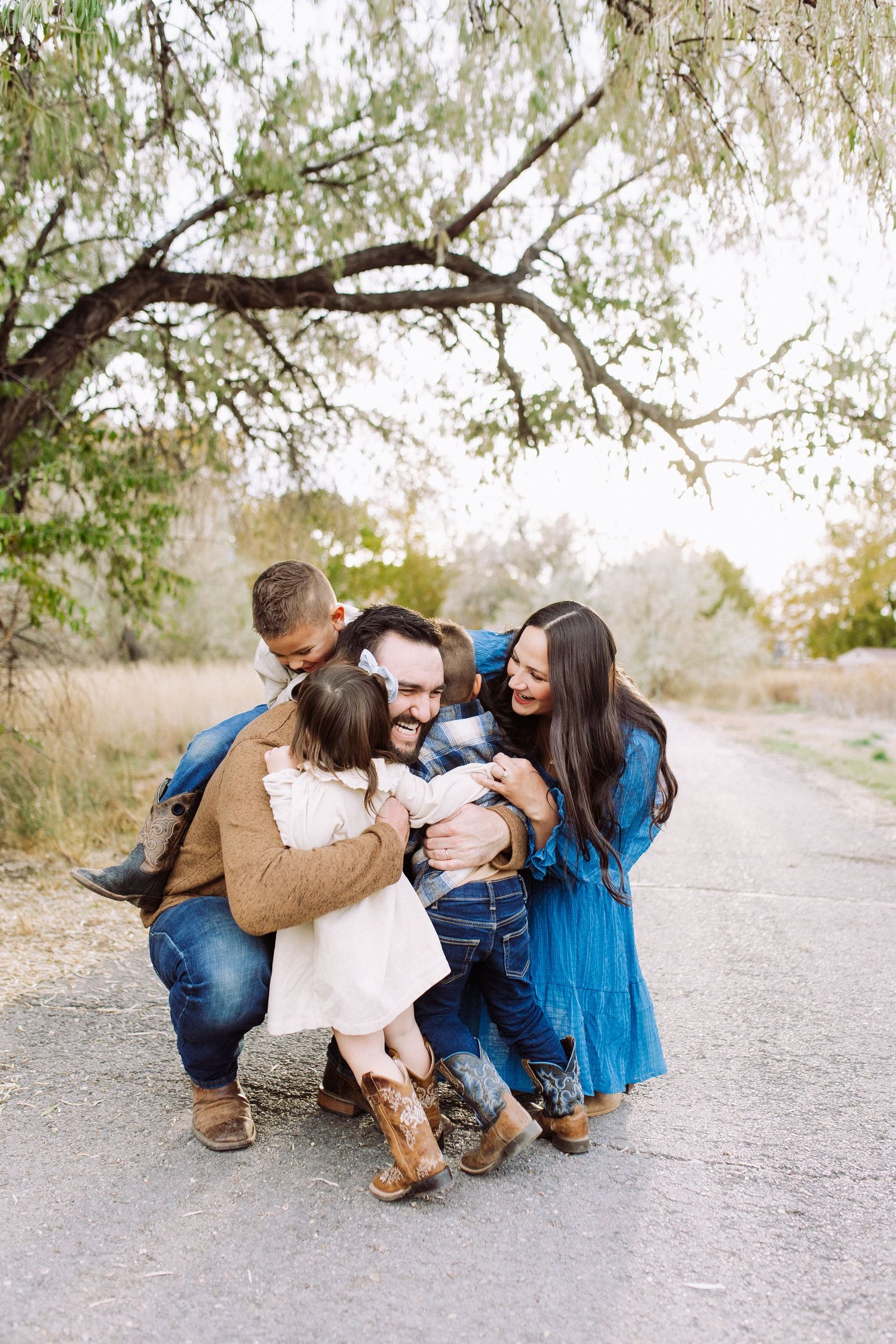 Family plays with dog on dirt path during outdoor photo session.