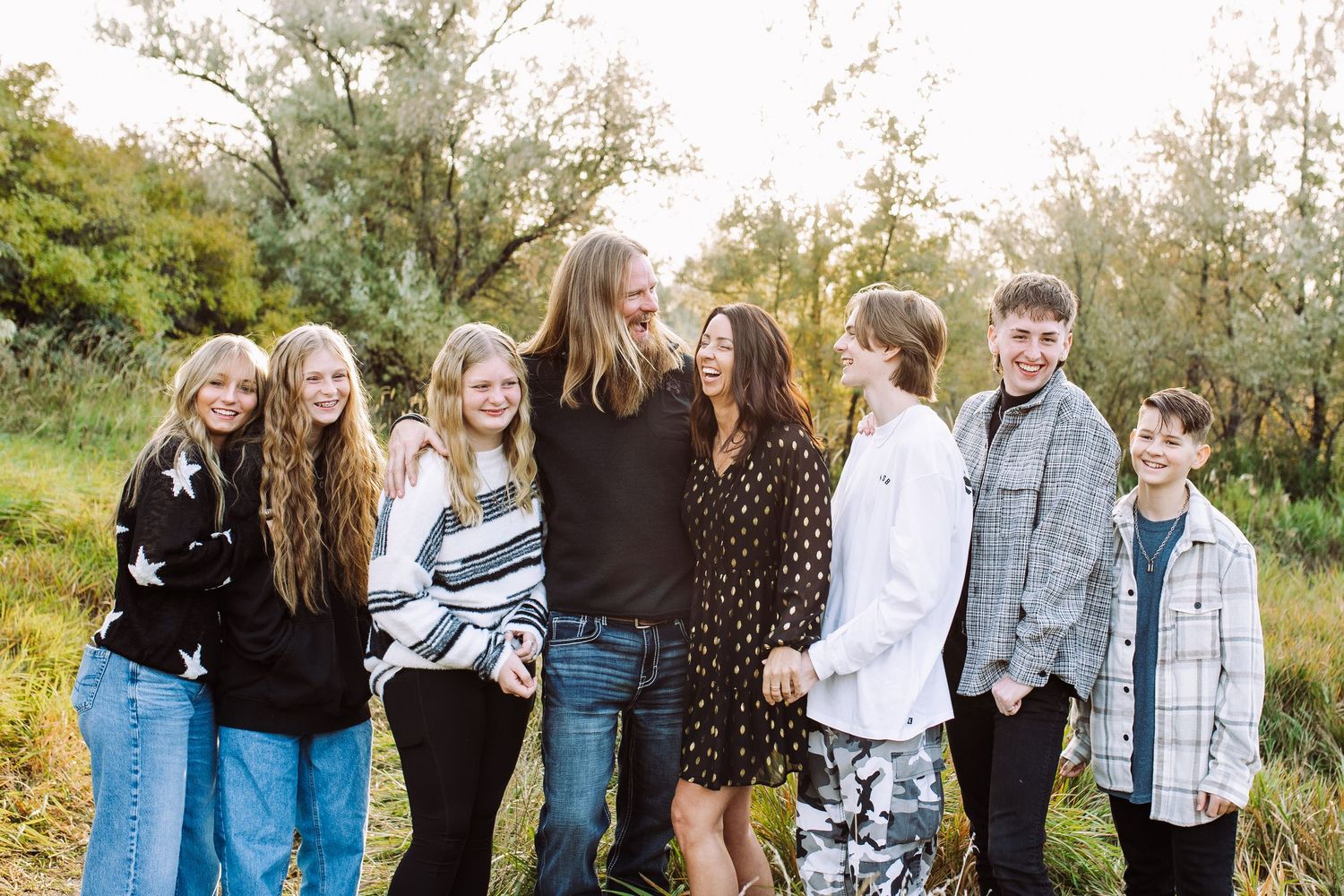 Large family group posing together outdoors in casual clothing for portrait session.