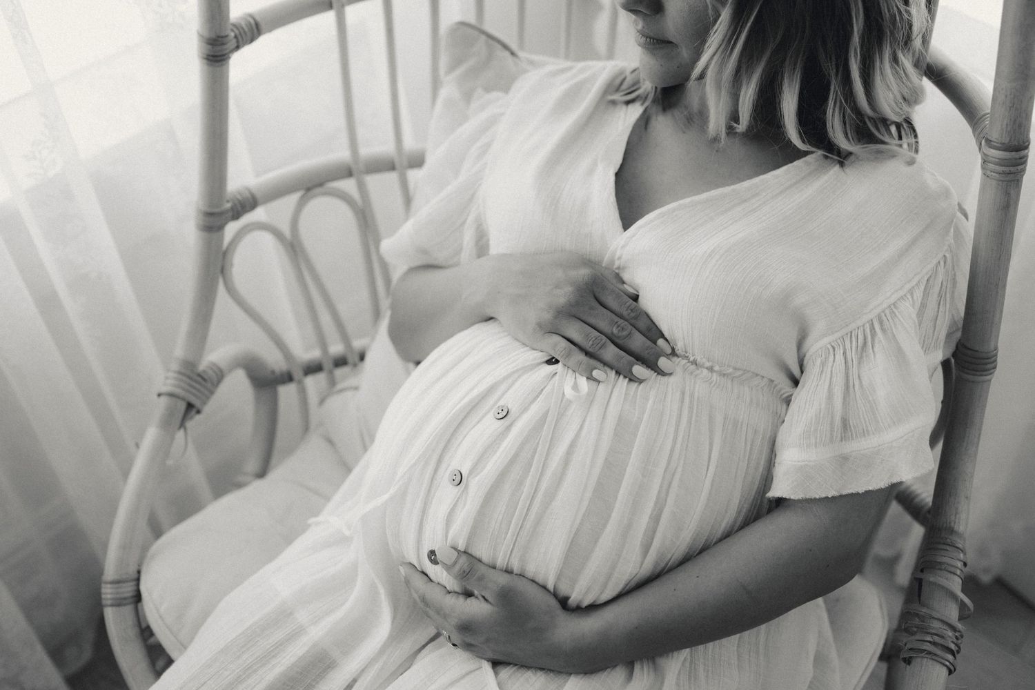 Intimate maternity photos in soft black and white showing pregnant belly.