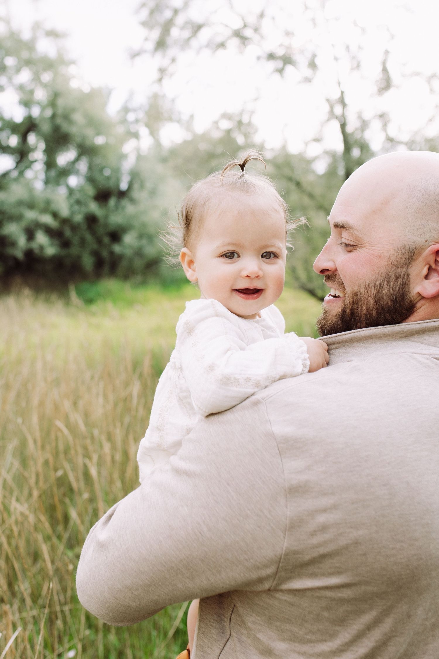 Tender moment between parent and baby captured in natural outdoor lighting.