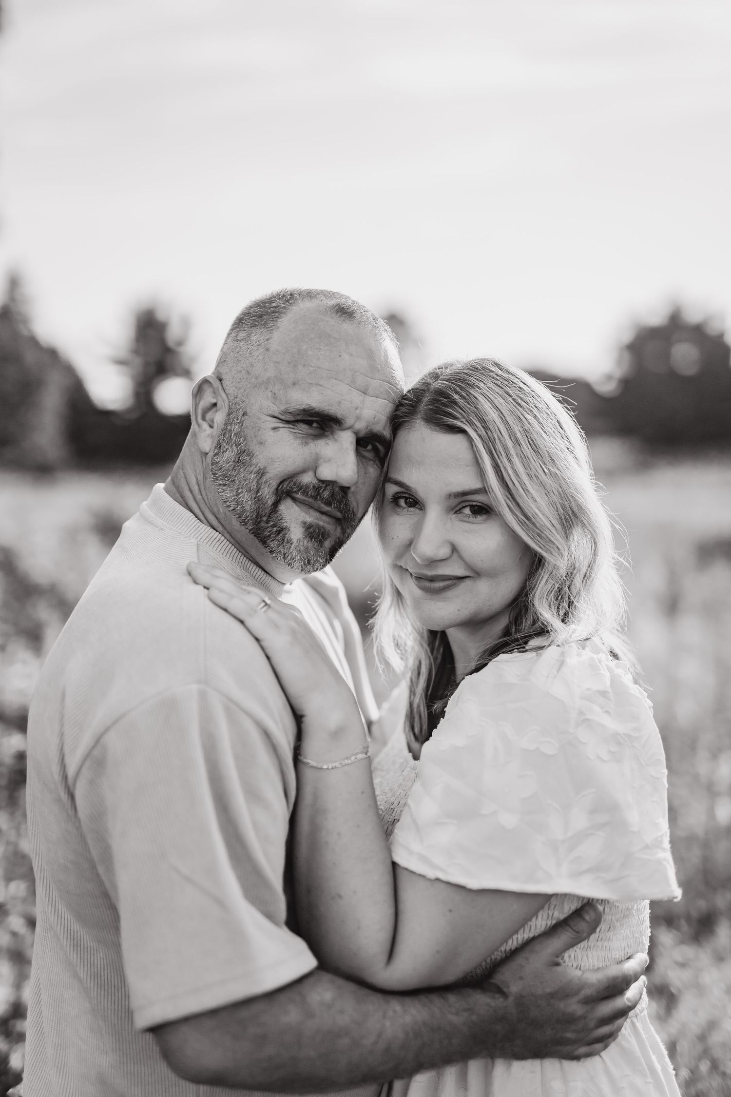 A couple shares intimate moments in an outdoor photoshoot series with a black and white filter effect.