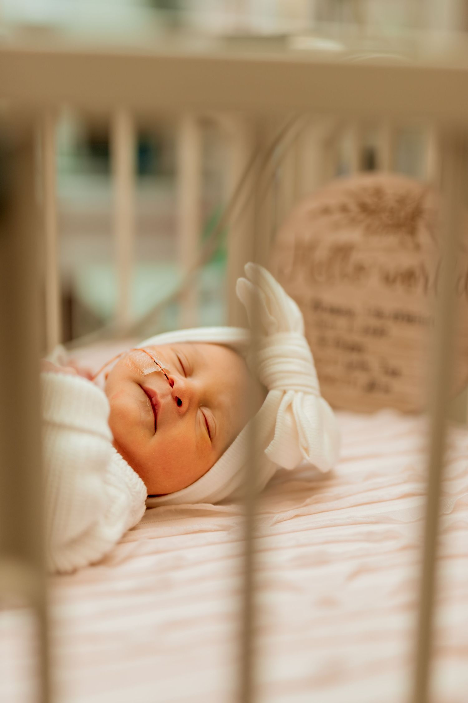 A newborn baby peacefully sleeping in white swaddling cloth on a light colored surface.