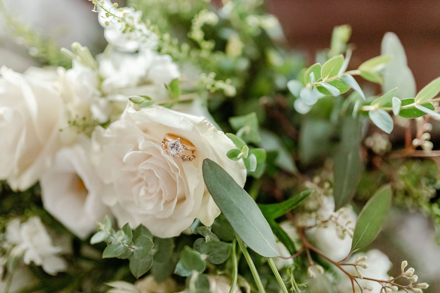 Close-up shot of delicate white roses and eucalyptus in a romantic wedding bouquet arrangement.