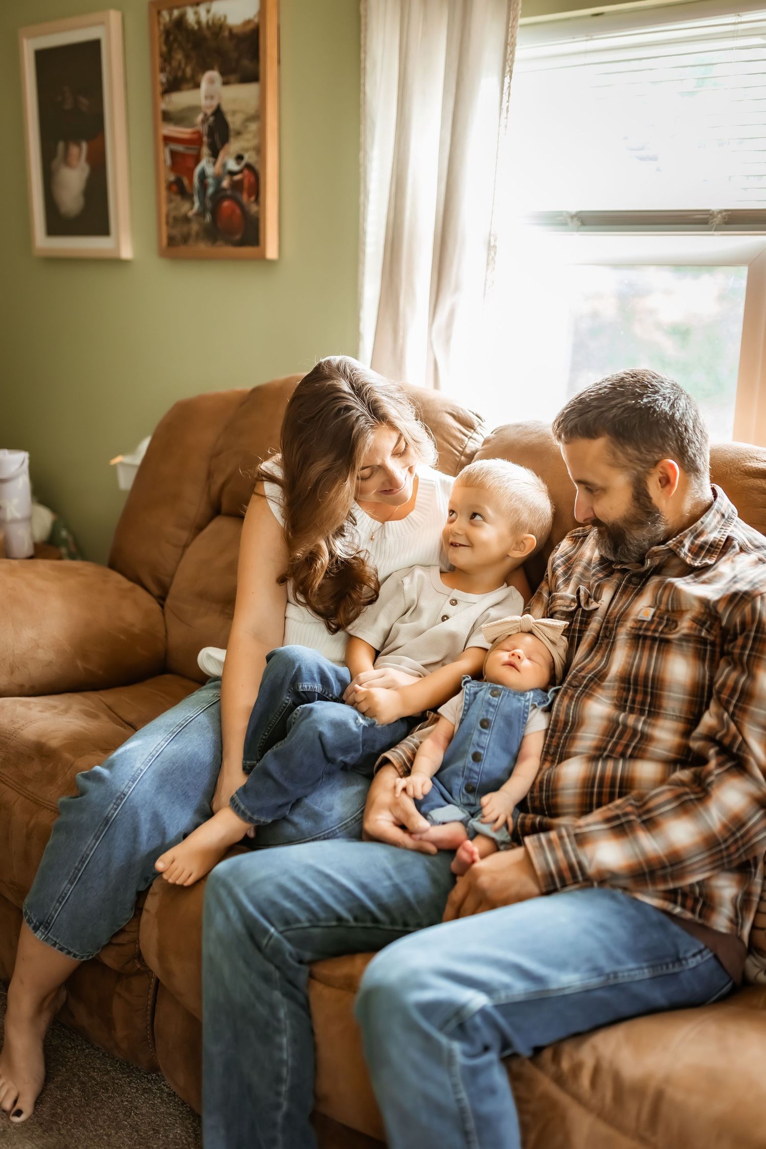 Family relaxing together on a brown leather couch in a cozy living room with soft natural lighting.