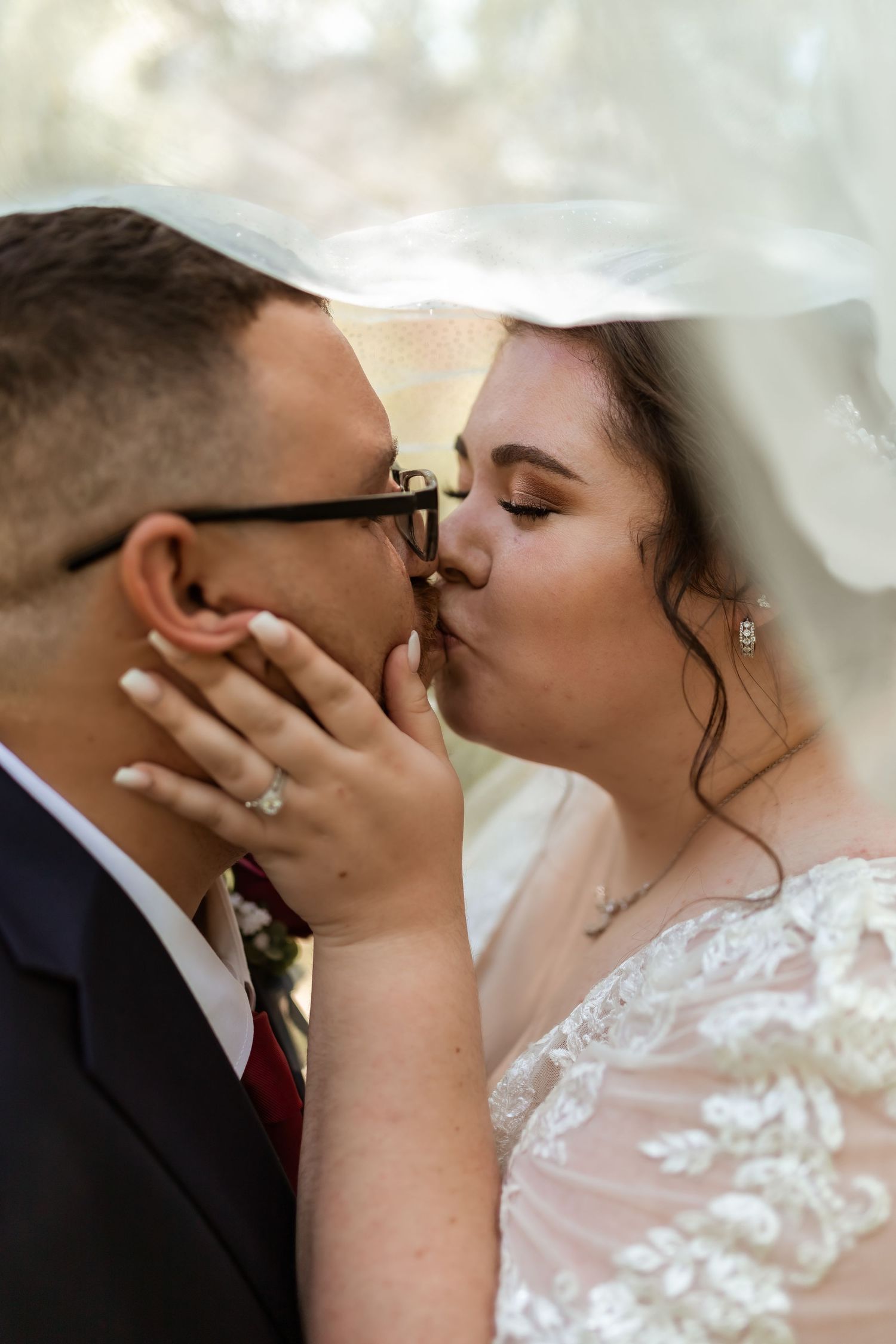A tender romantic wedding kiss moment under a flowing white veil.