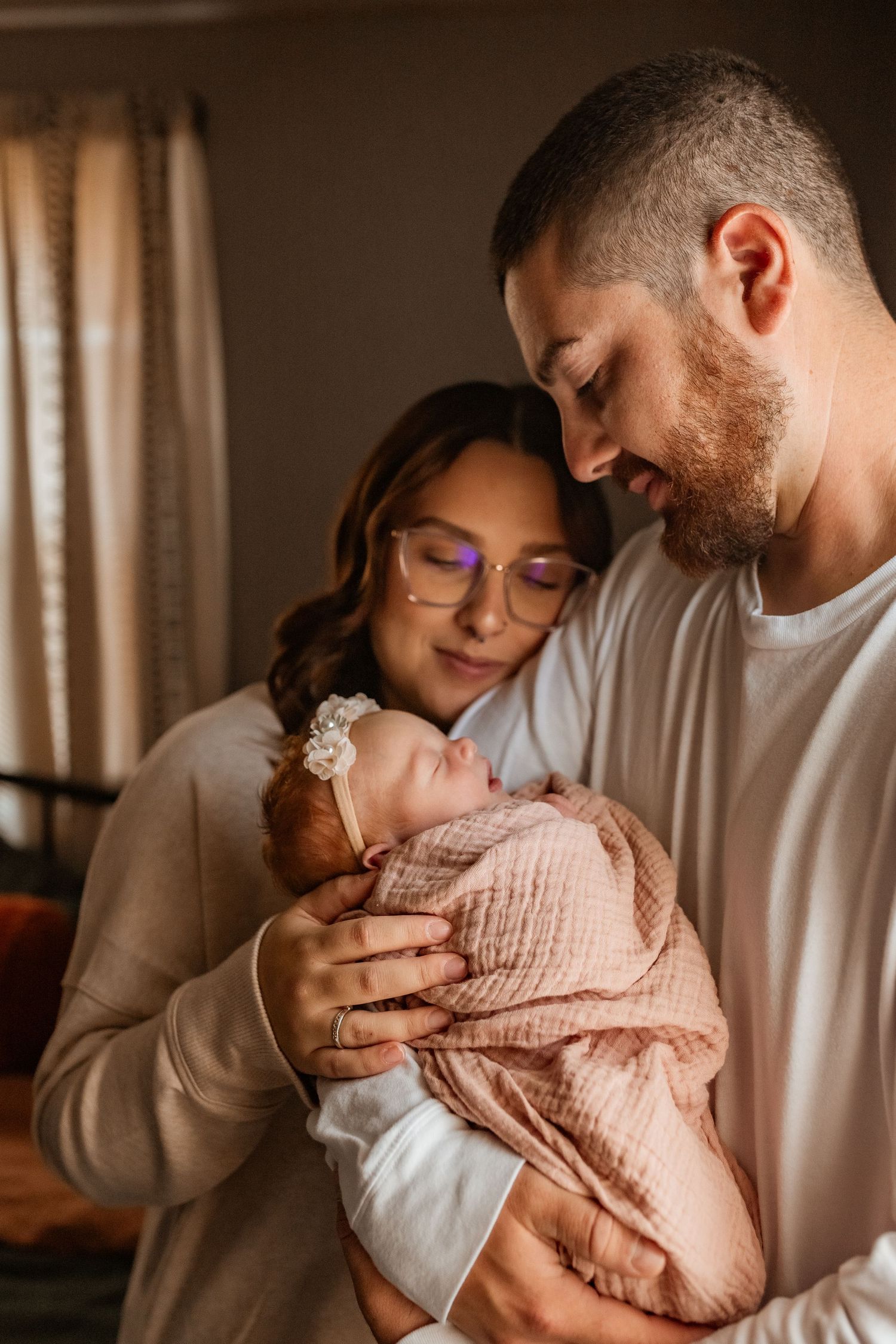 A tender moment between parent and baby in soft natural light near a window.