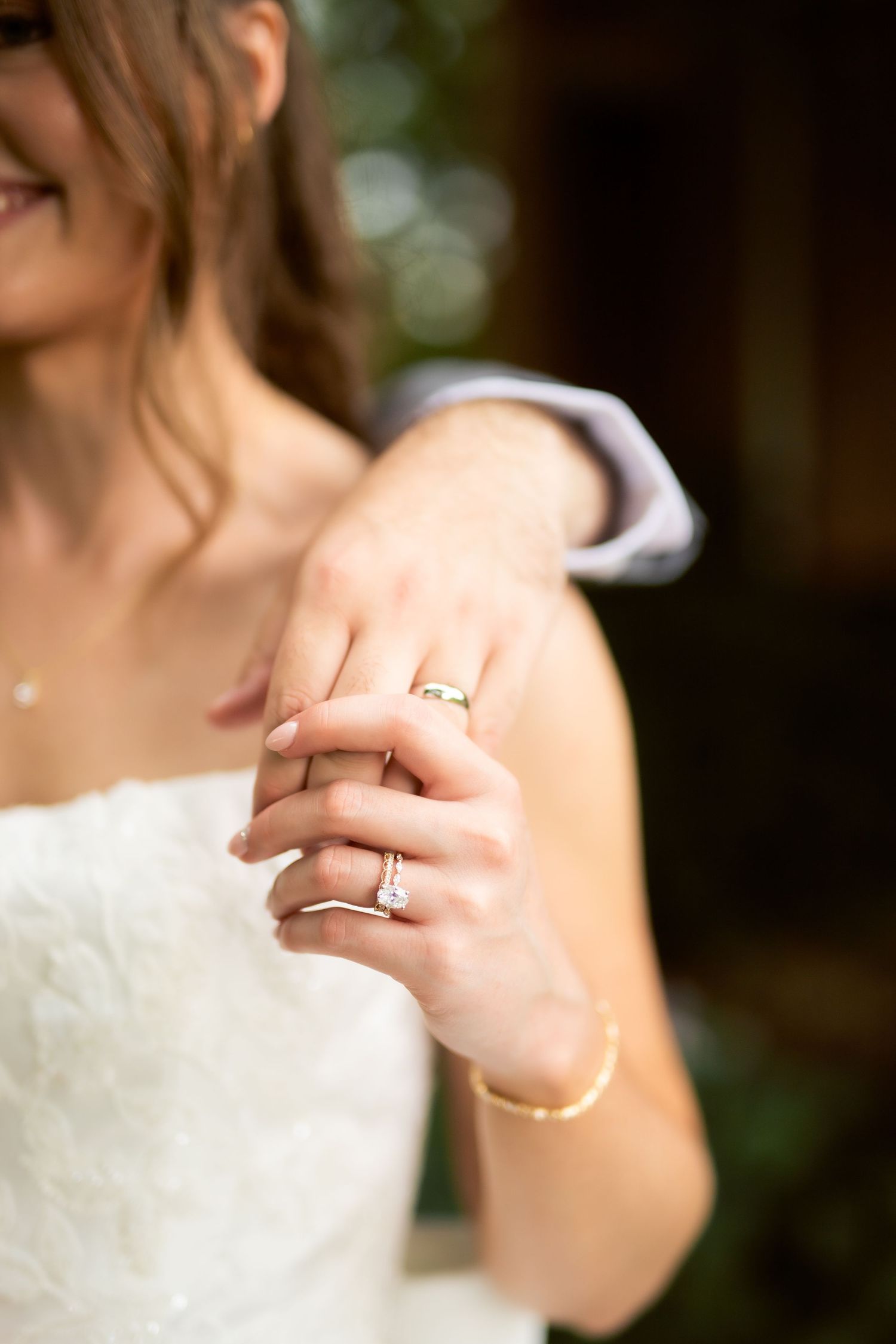 Close-up of bride and groom hands showing diamond engagement ring and wedding band on their wedding day.