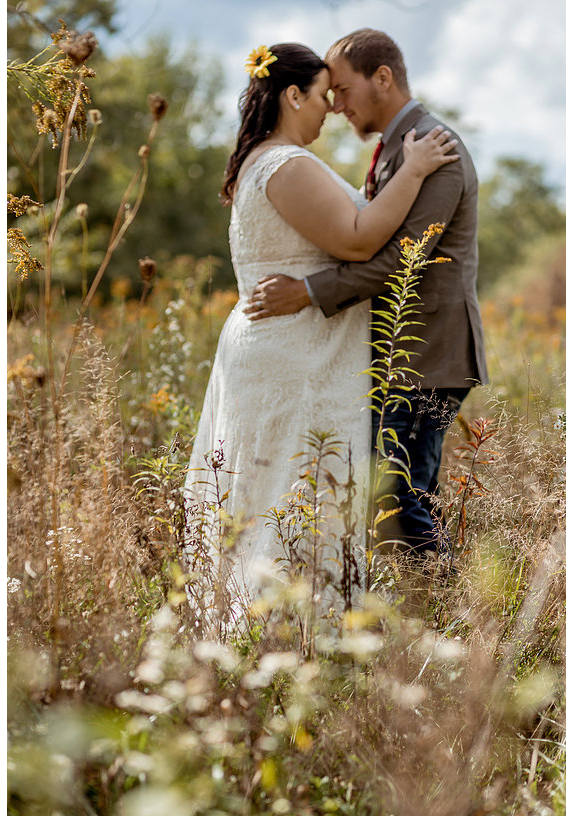 A romantic wedding portrait of a couple embracing in a wildflower meadow.
