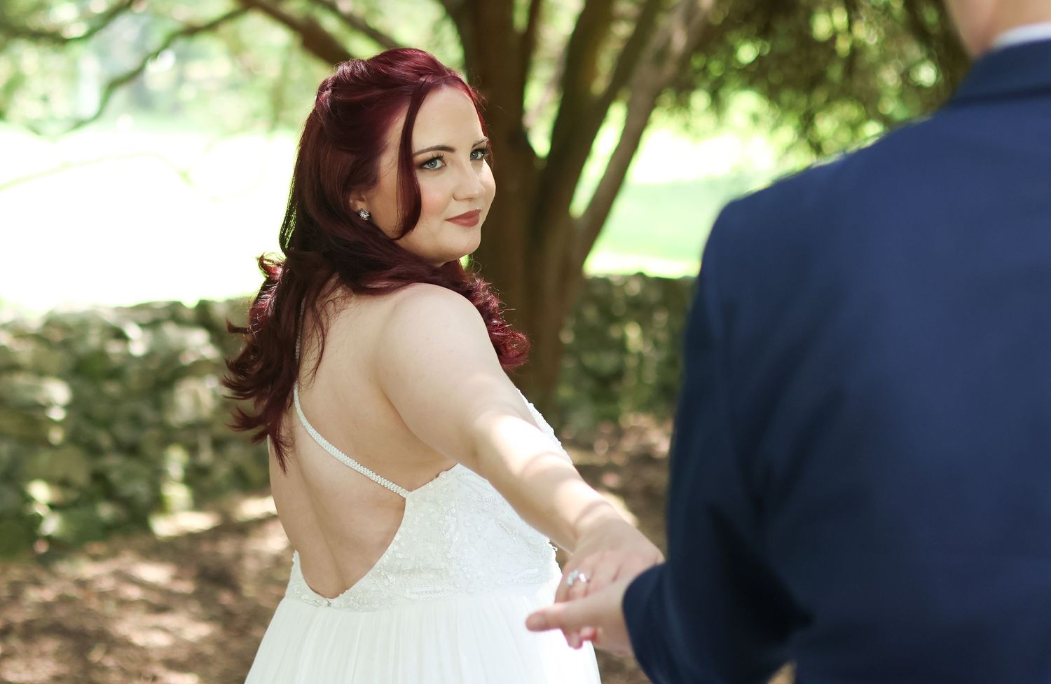 A couple shares a tender moment outdoors during their wedding photo session in a natural garden setting.