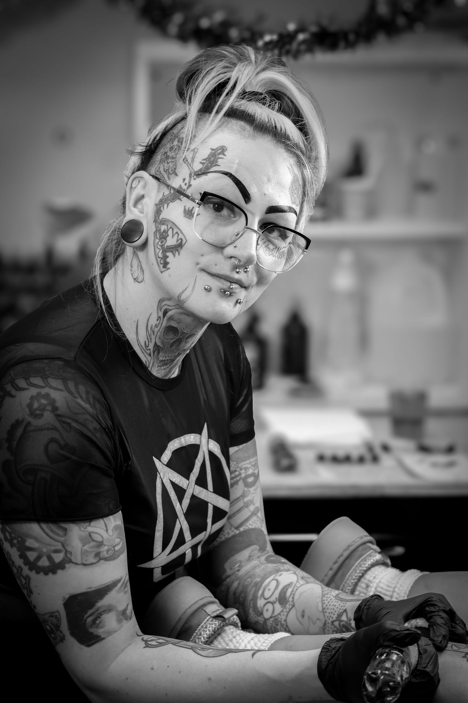 Black and white photos show a tattoo artist working intently at their craft in a studio setting.