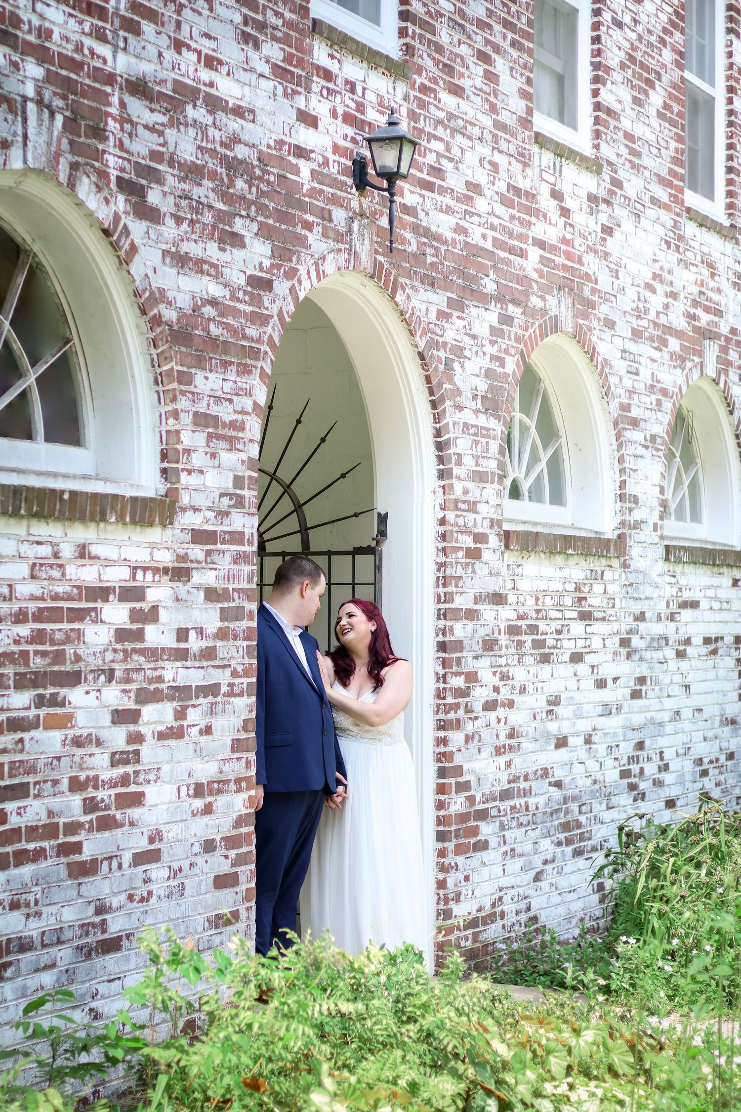 A romantic wedding couple shares intimate moments in a series of photos against a white brick archway.
