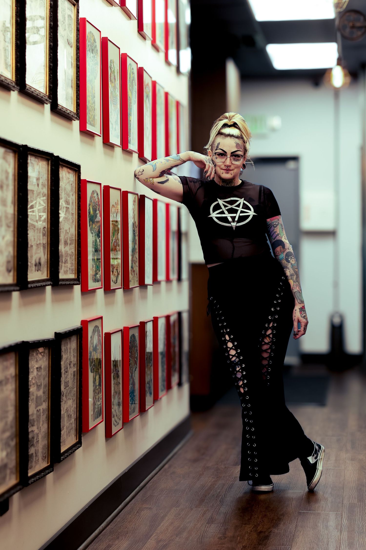 Three connected photos show someone in a black dress posing dramatically in a hallway with framed artwork on the walls.