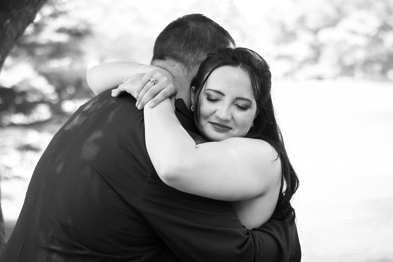 A series of black and white photos showing tender moments between a couple embracing outdoors.