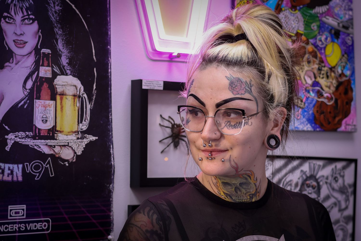 A wall display of artistic portraits and illustrations in purple and pink lighting creates a moody aesthetic atmosphere.