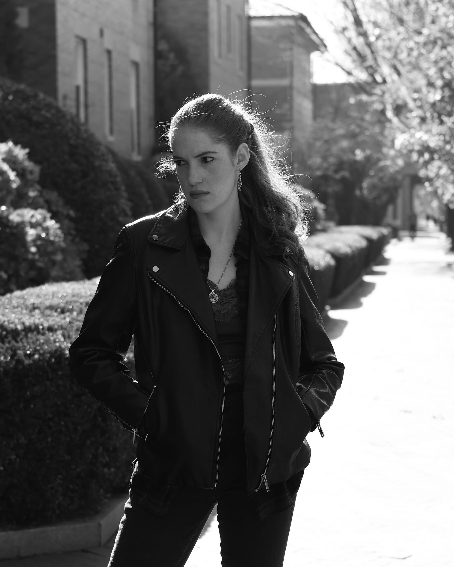 Person in black leather jacket walking outdoors in black and white photography series.