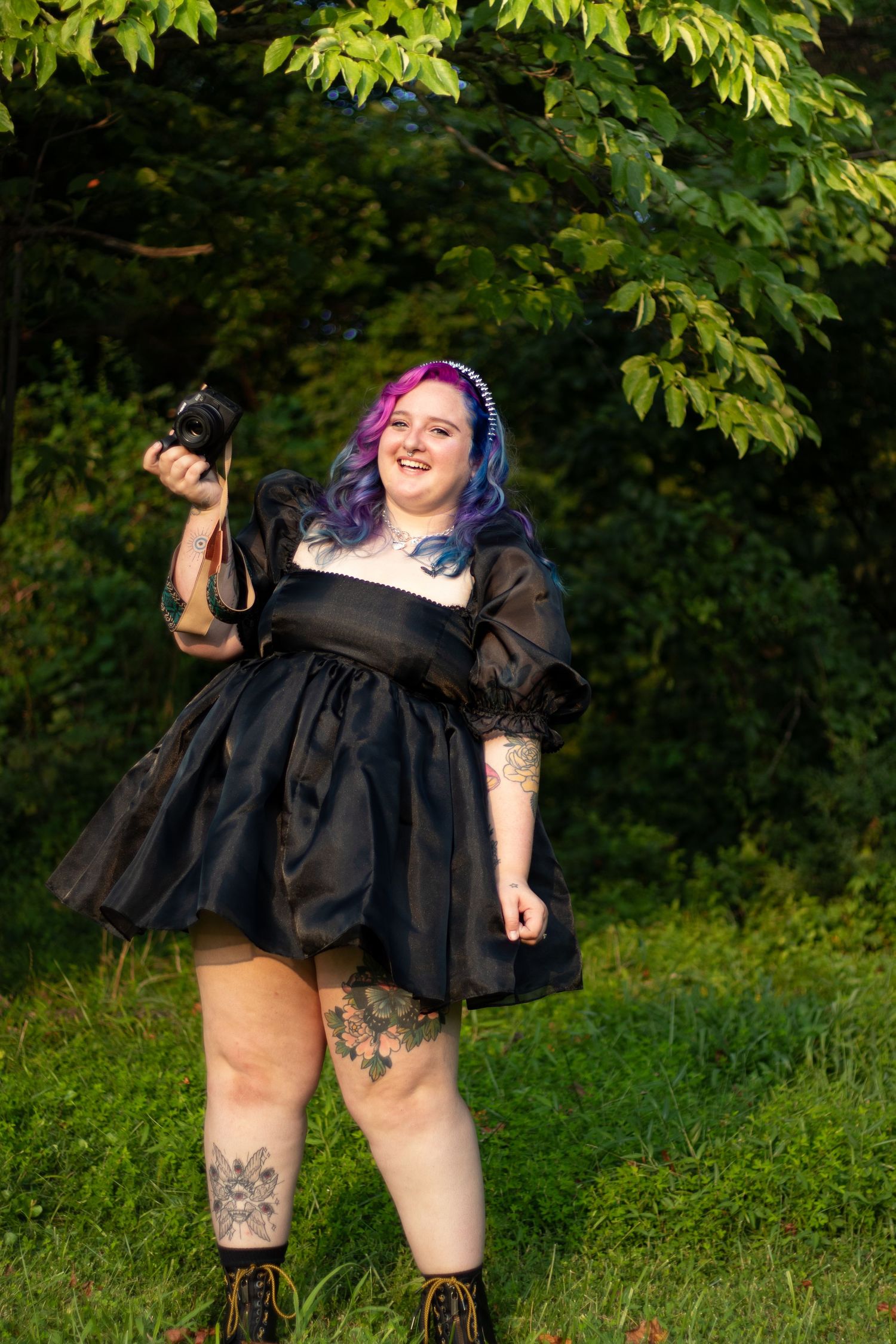 A series of outdoor photos showing someone in a black dress and purple hair posing expressively against lush green foliage.
