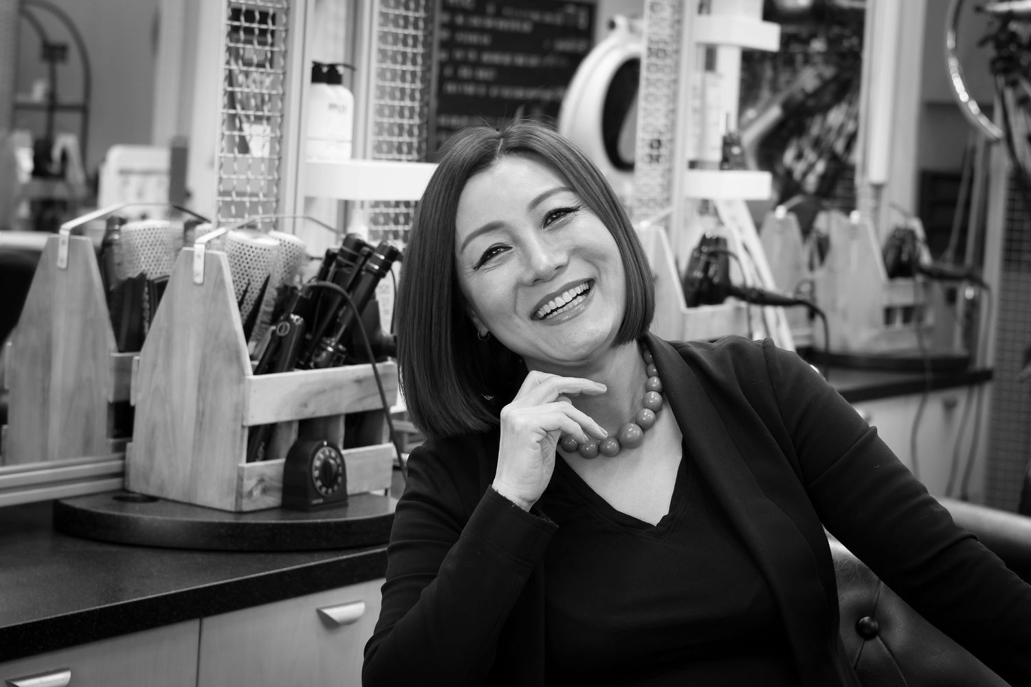 A candid black and white photo shows a joyful expression at a restaurant counter with bottles in the background.