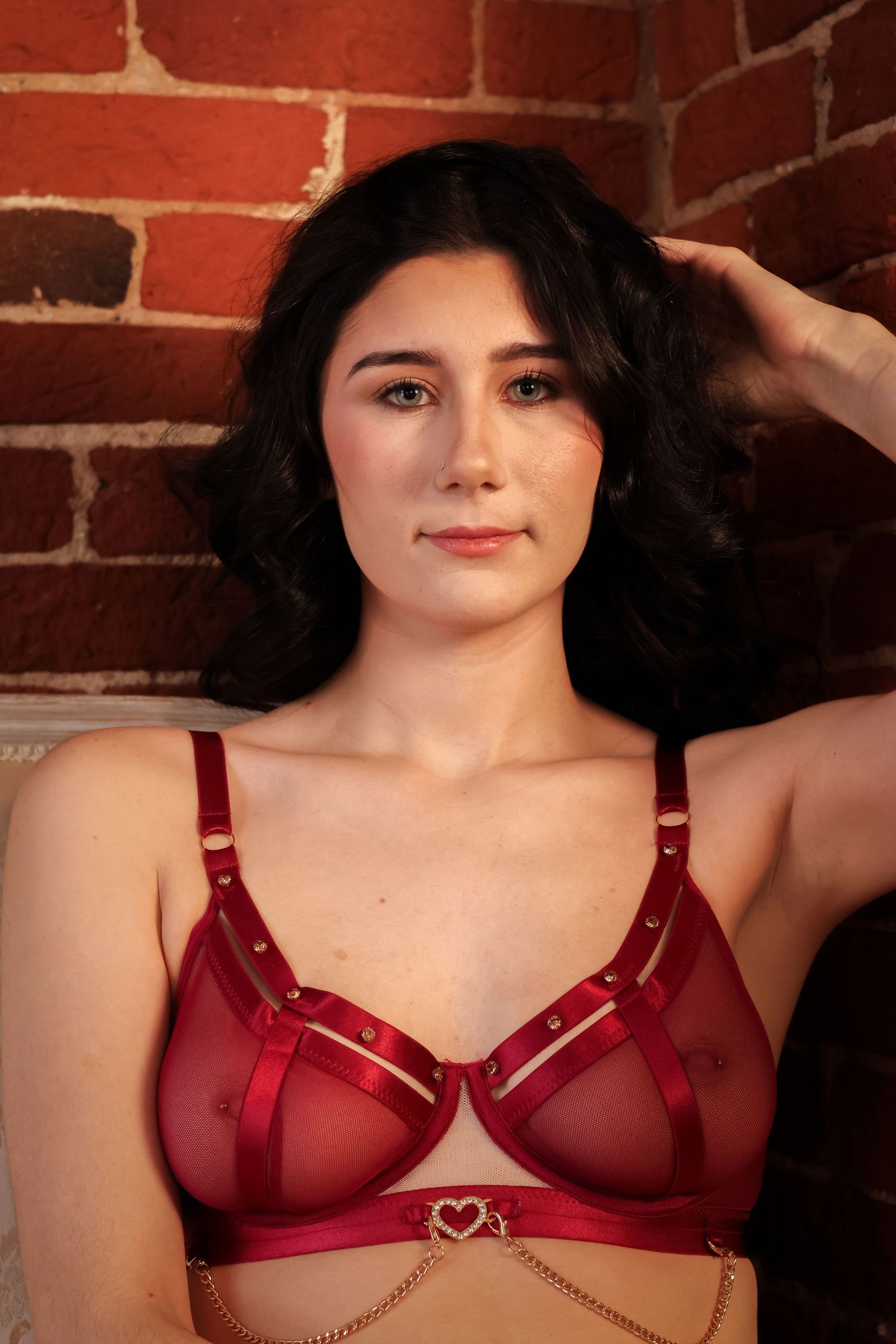 A collection of red lingerie bra product photos against a brick wall background.