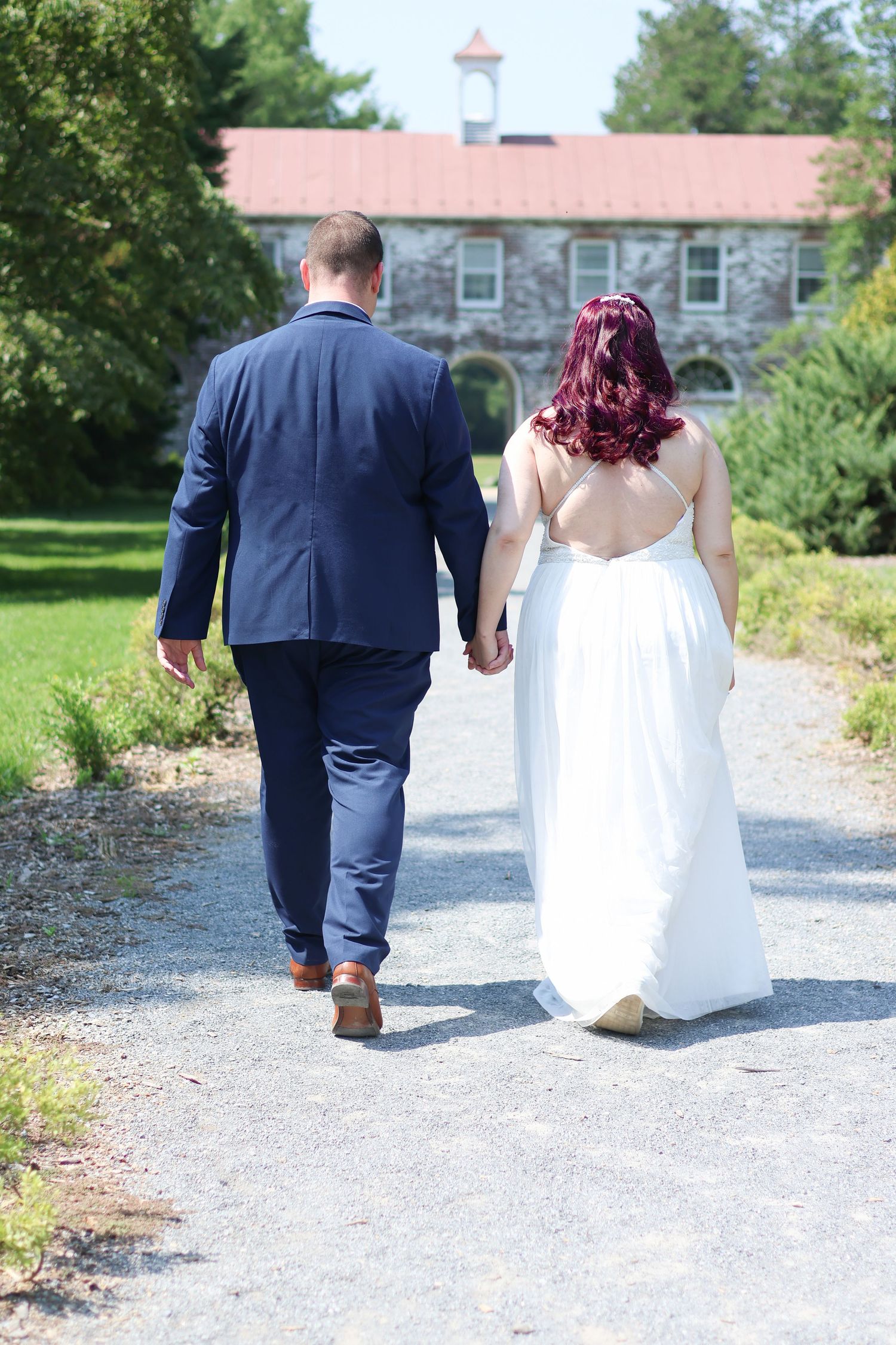 A couple in wedding attire walks away down a gravel path showing their backs in a series of similar photos.