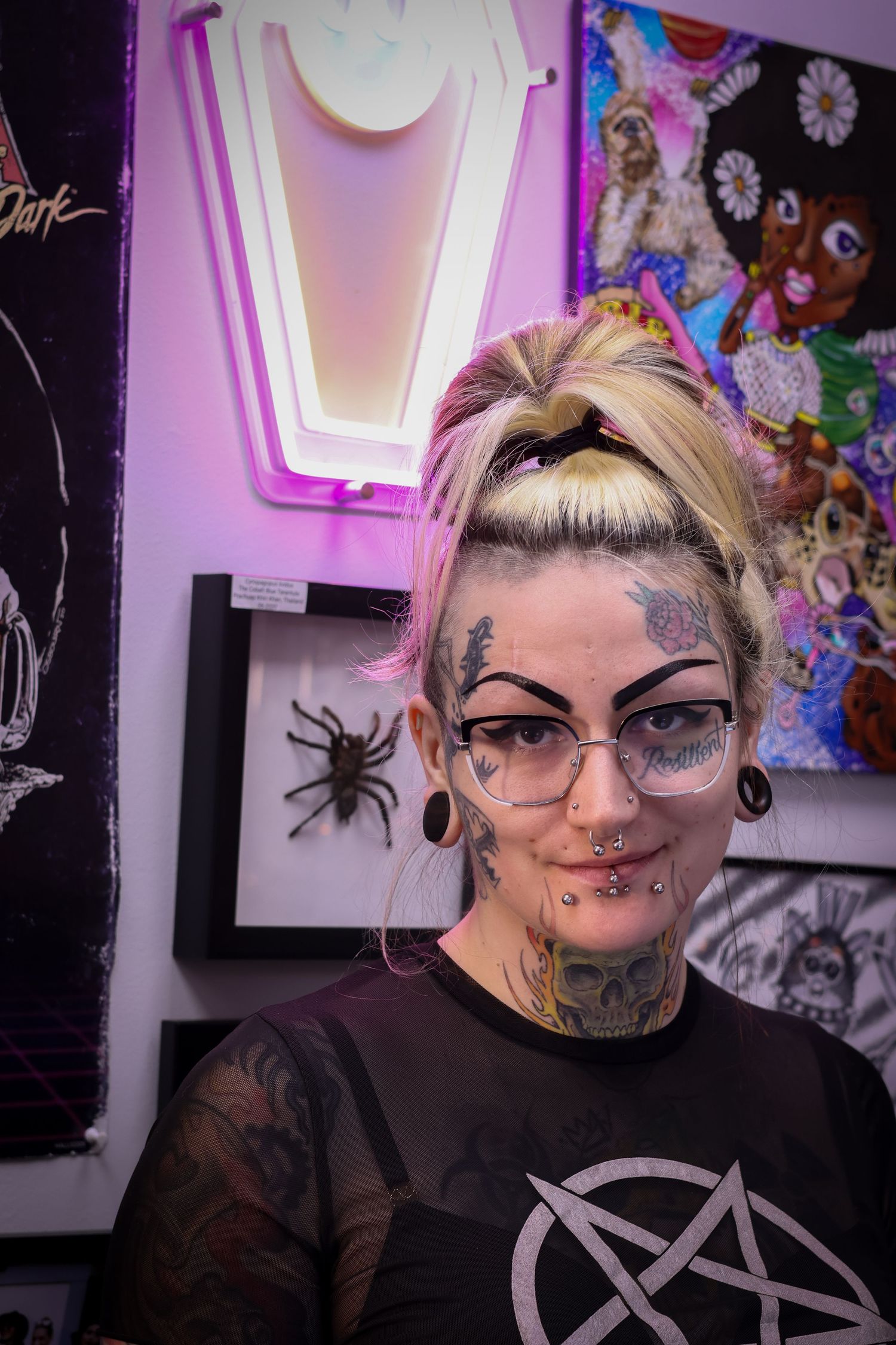 Alternative style portrait series showing artistic makeup and piercings in purple-lit gallery setting.