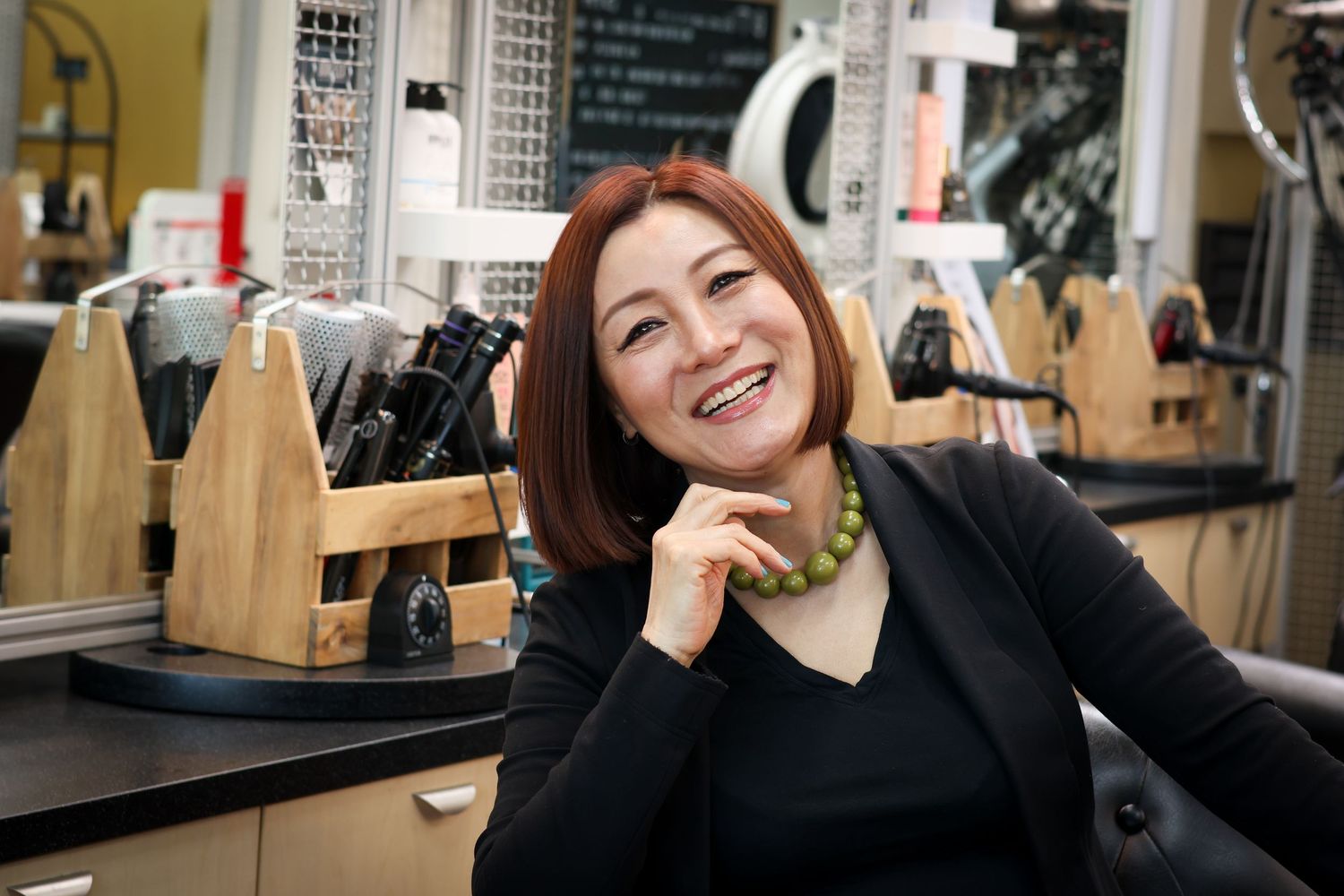 A coffee shop barista smiles while working behind a counter with coffee equipment and wooden decor.